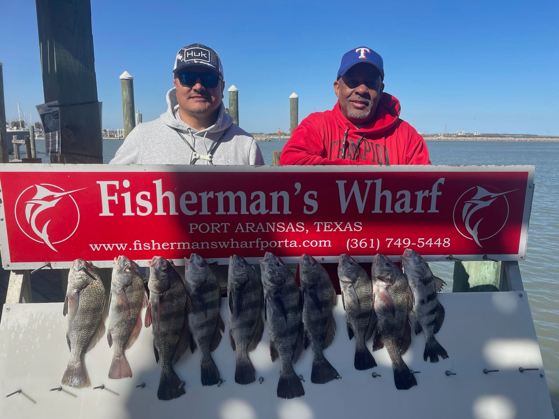 Two men holding a sign that says fisherman 's wharf
