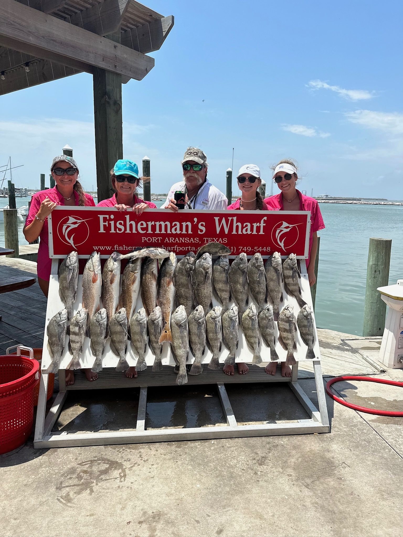 A group of people standing next to a rack of fish.