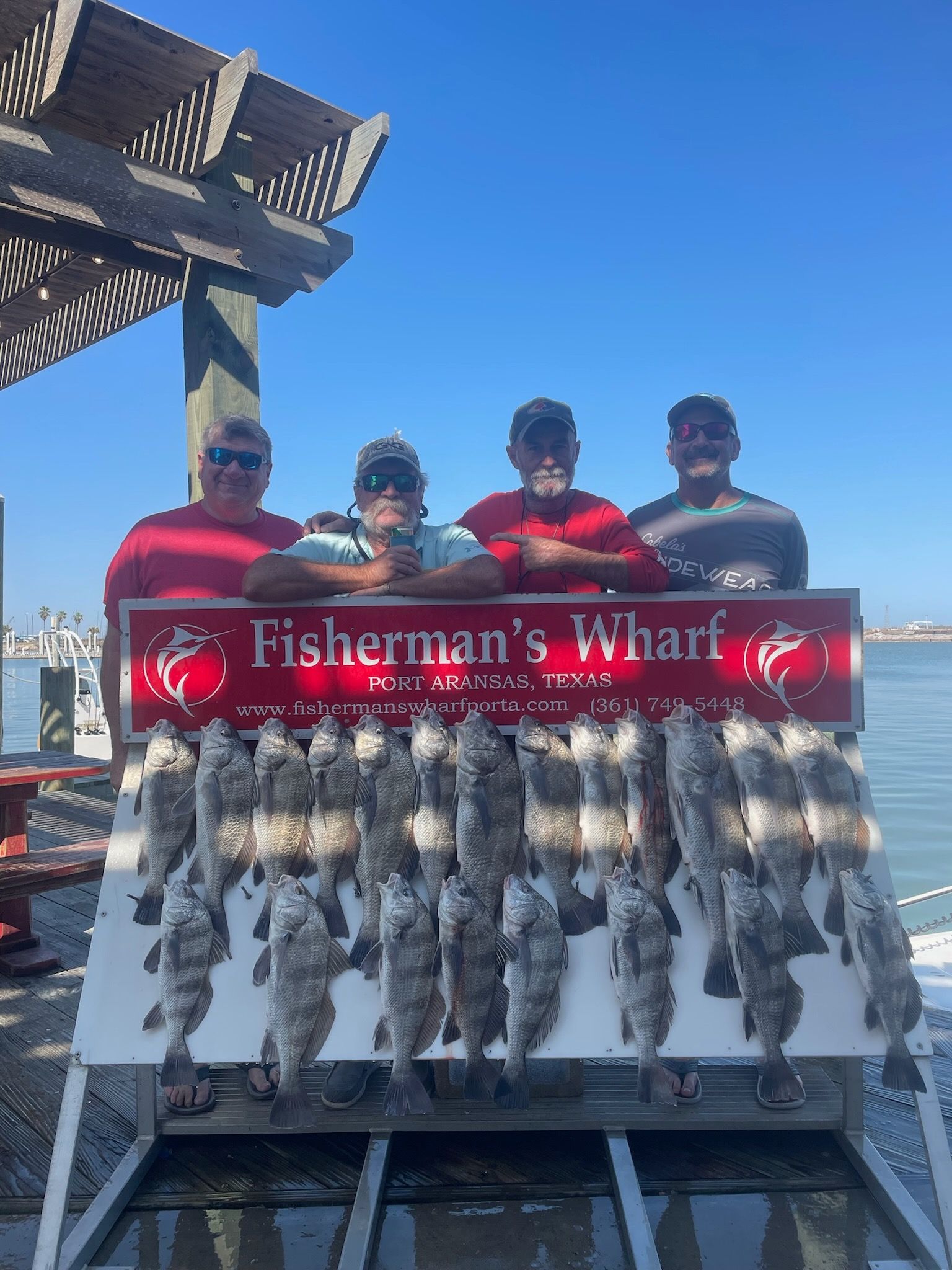 A group of men are standing next to a sign that says fisherman 's wharf.