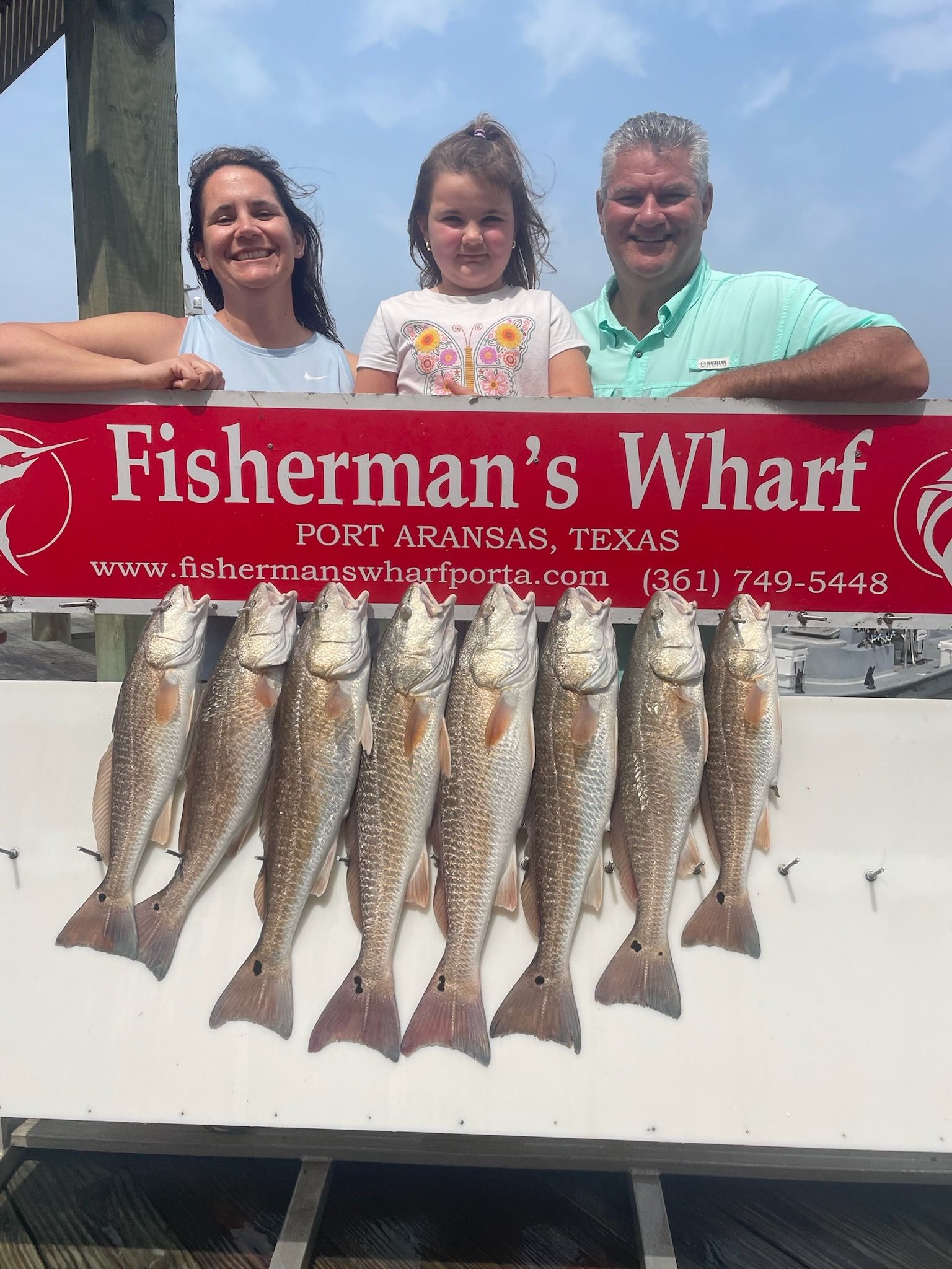 A family is standing next to a sign that says fisherman 's wharf.