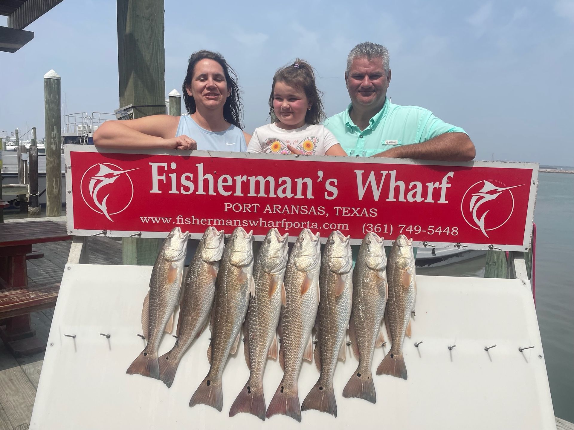 A group of people standing next to a sign that says fisherman 's wharf