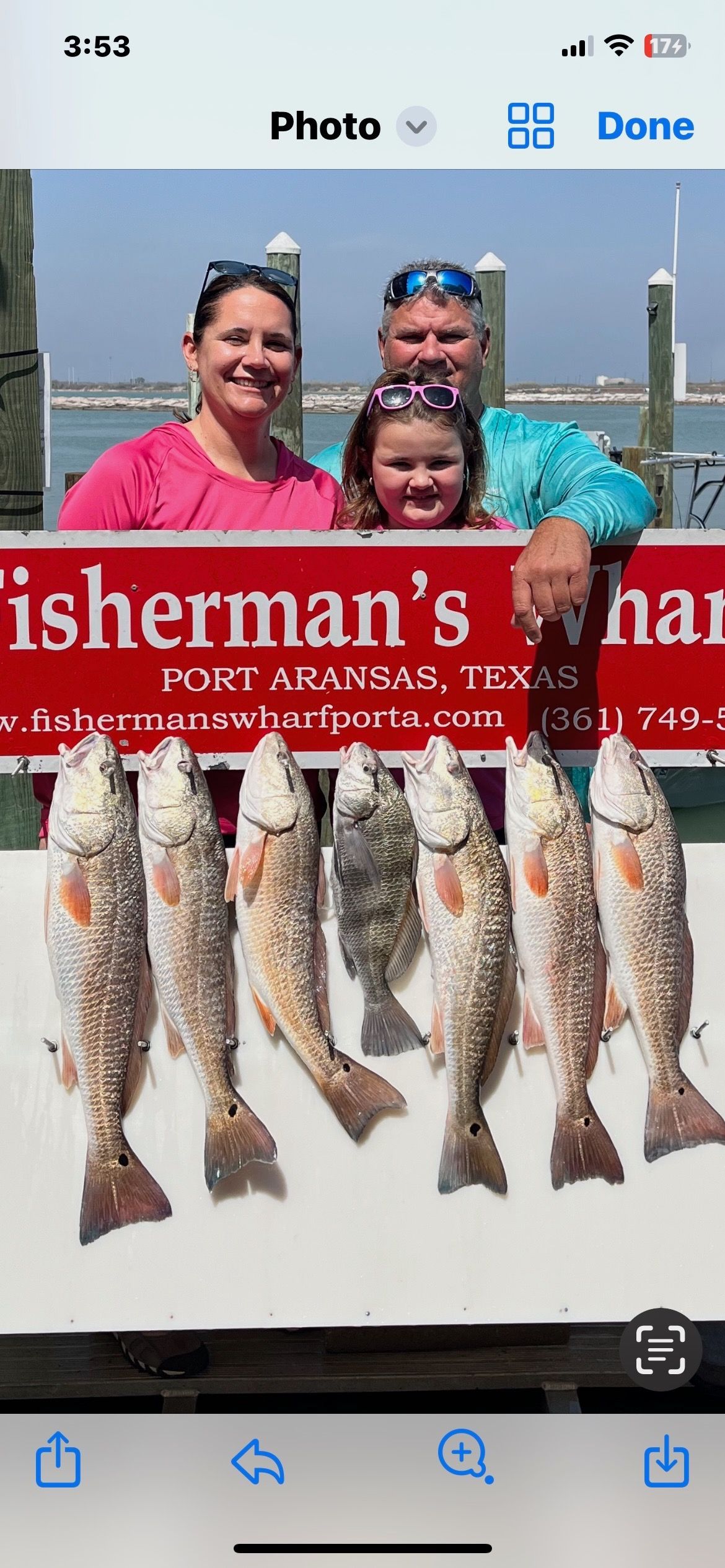 A family is holding a sign that says fisherman 's harbor.