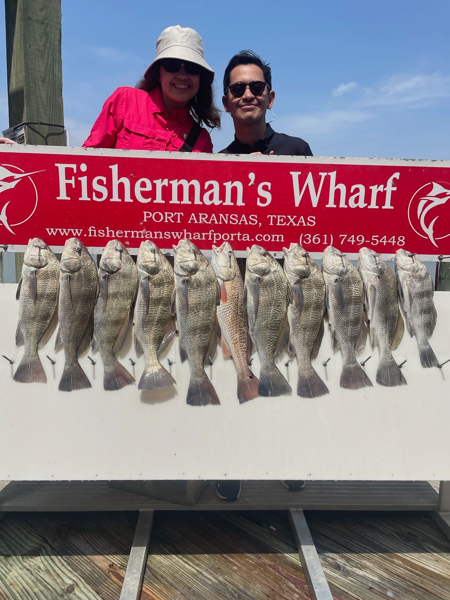 A man and a woman are holding a sign that says fisherman 's wharf.