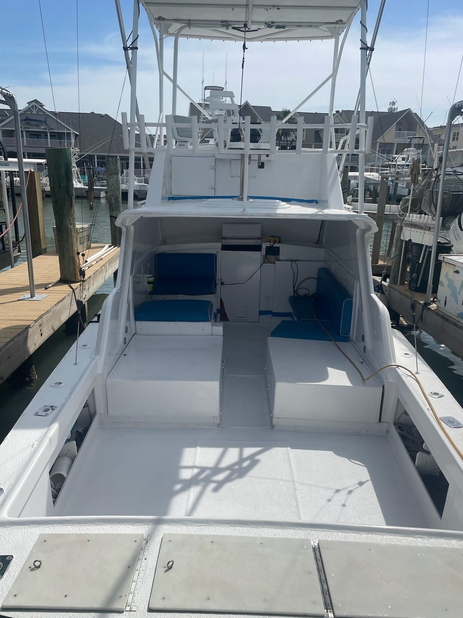 A white boat with blue seats is docked at a dock.