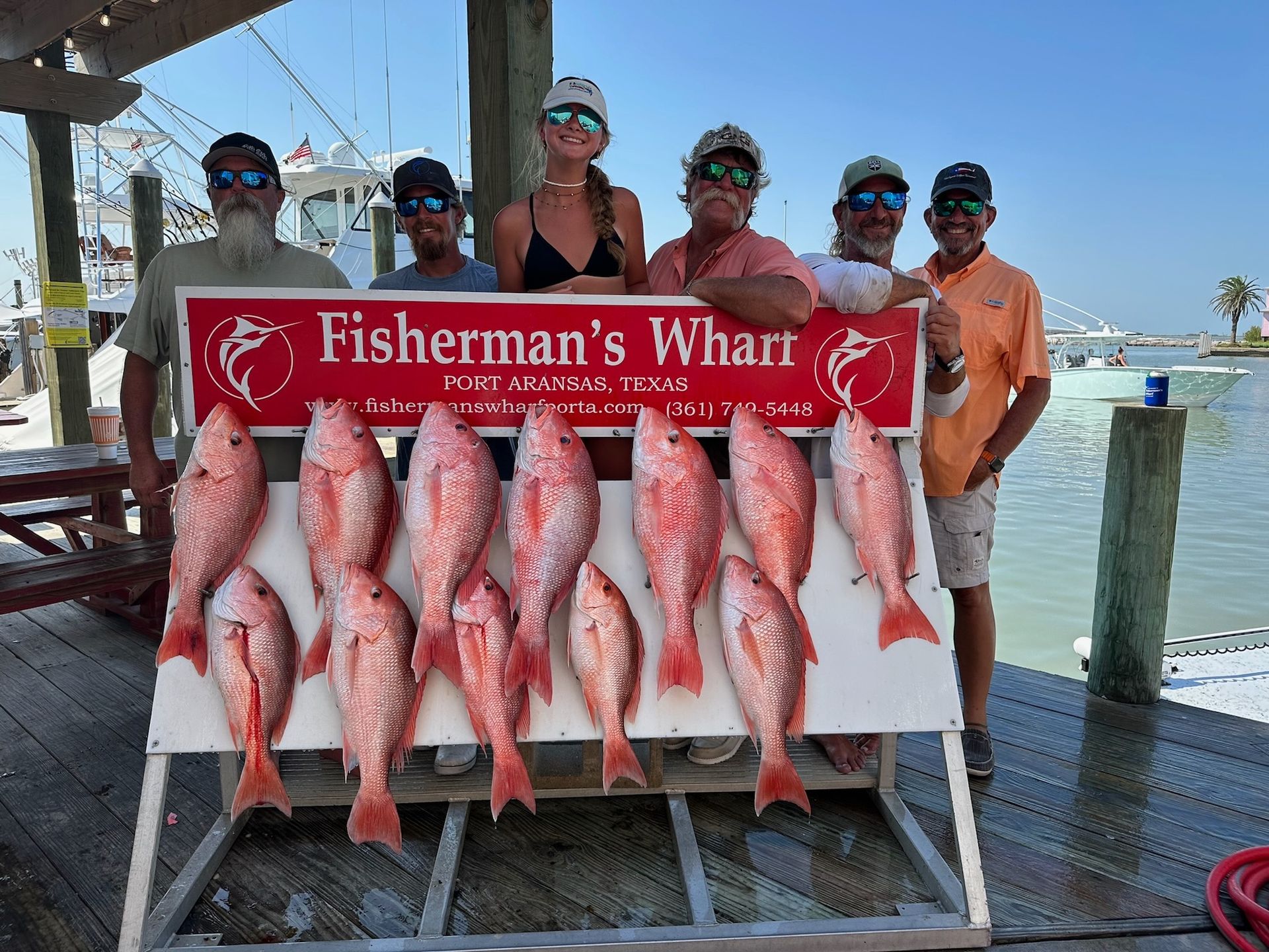 A group of people standing next to a sign that says fisherman 's wharf.