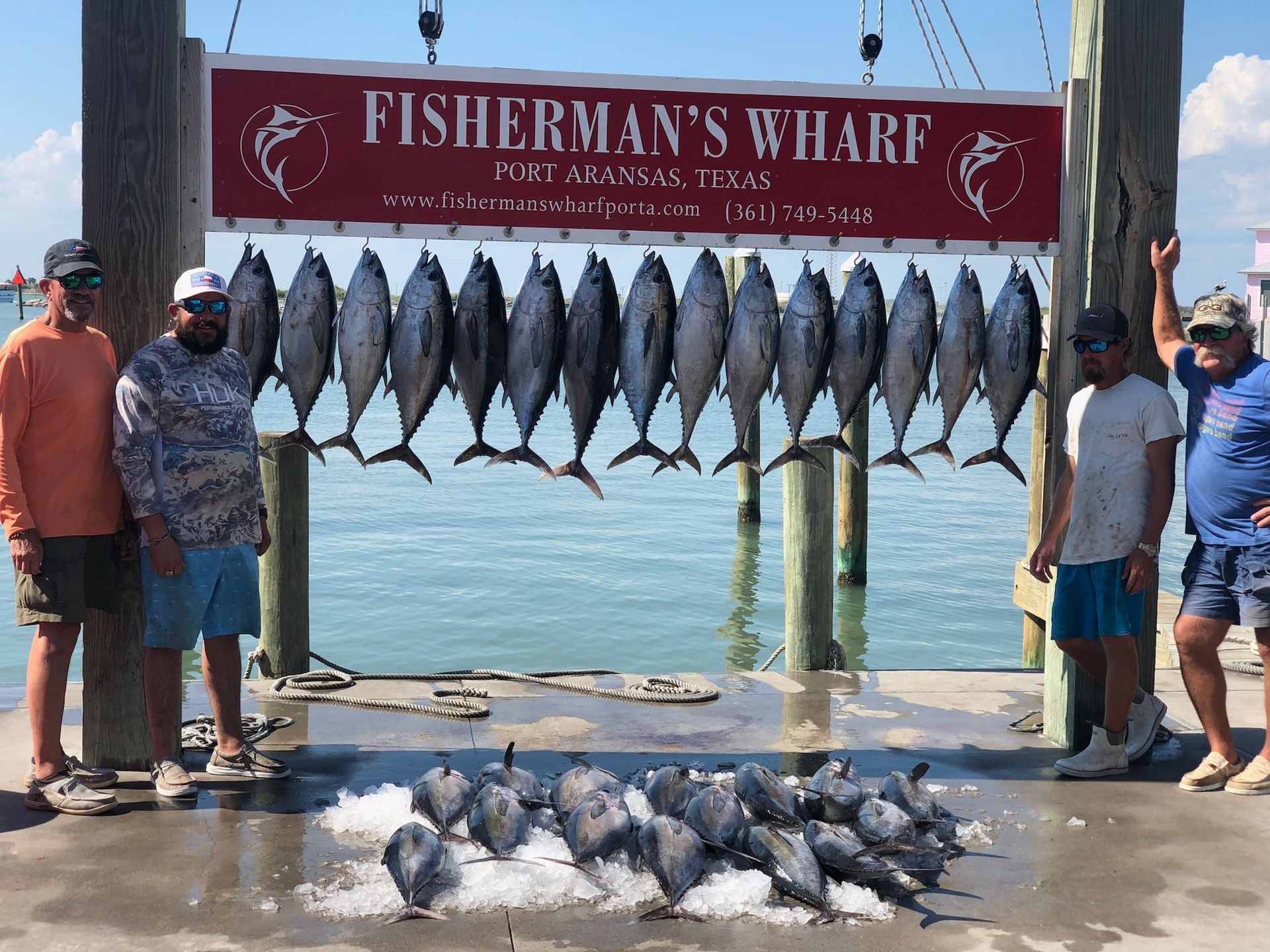 A group of men standing in front of a sign that says fisherman 's wharf