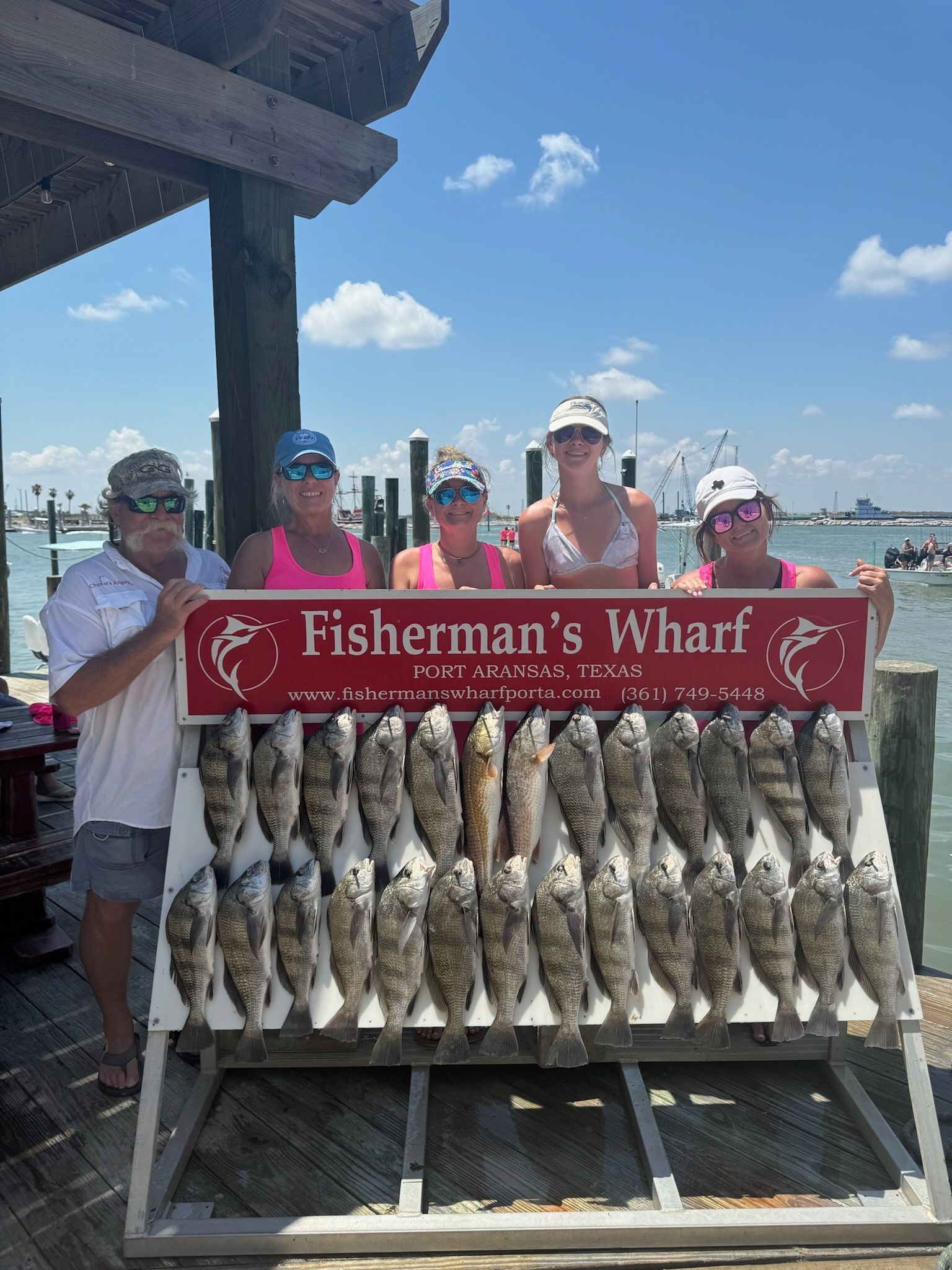 A group of people standing next to a rack of fish.
