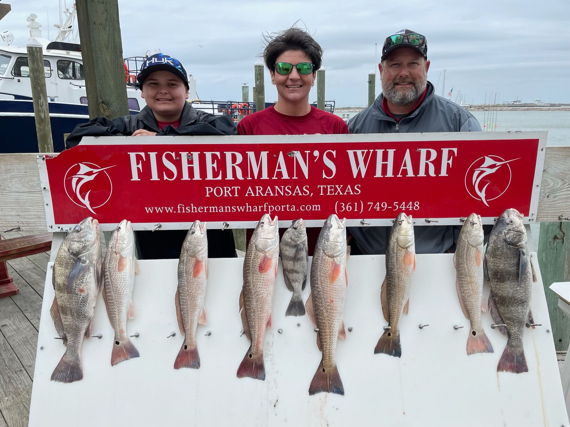 A group of people are standing in front of a sign that says fisherman 's wharf.