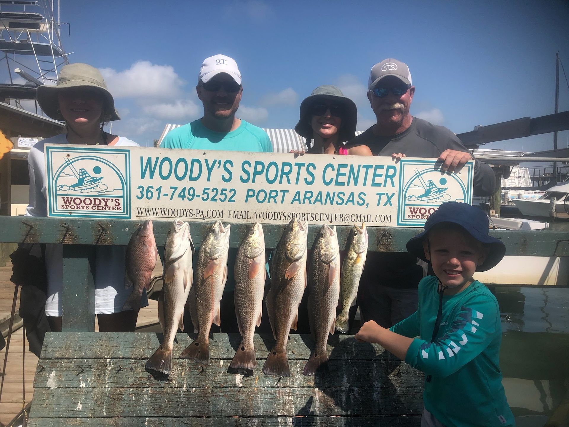 A group of people are holding a sign that says woody 's sports center.