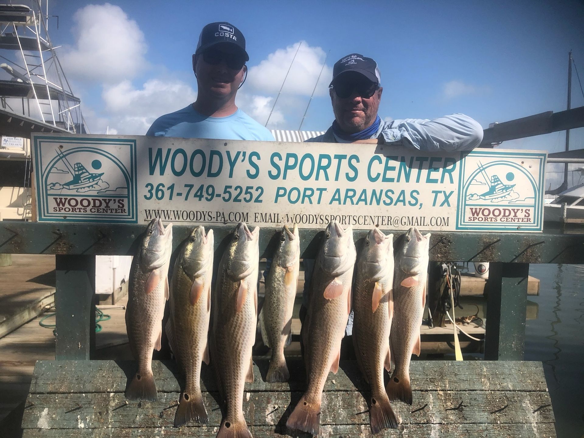 Two men are holding a sign that says woody 's sports center.