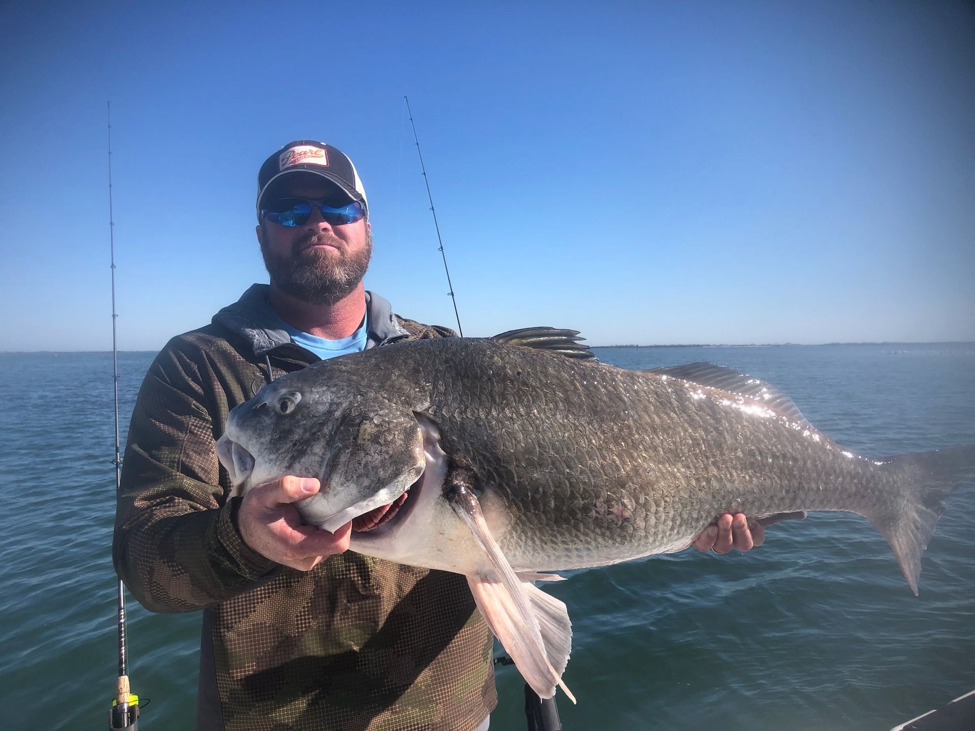 A man is holding a large fish in his hands on a boat.