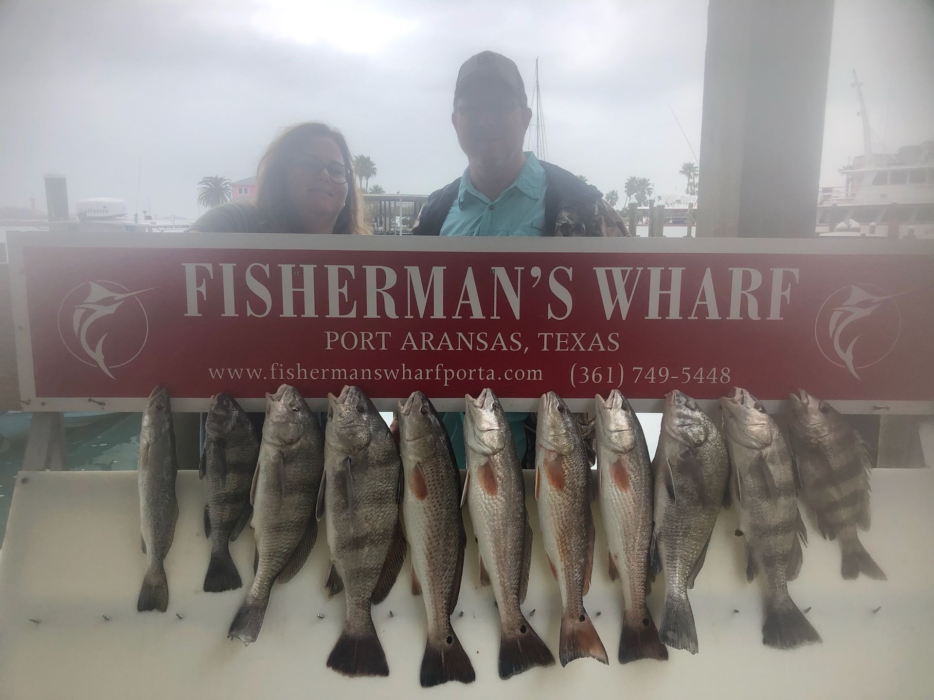 A man and woman holding a sign that says fisherman 's wharf