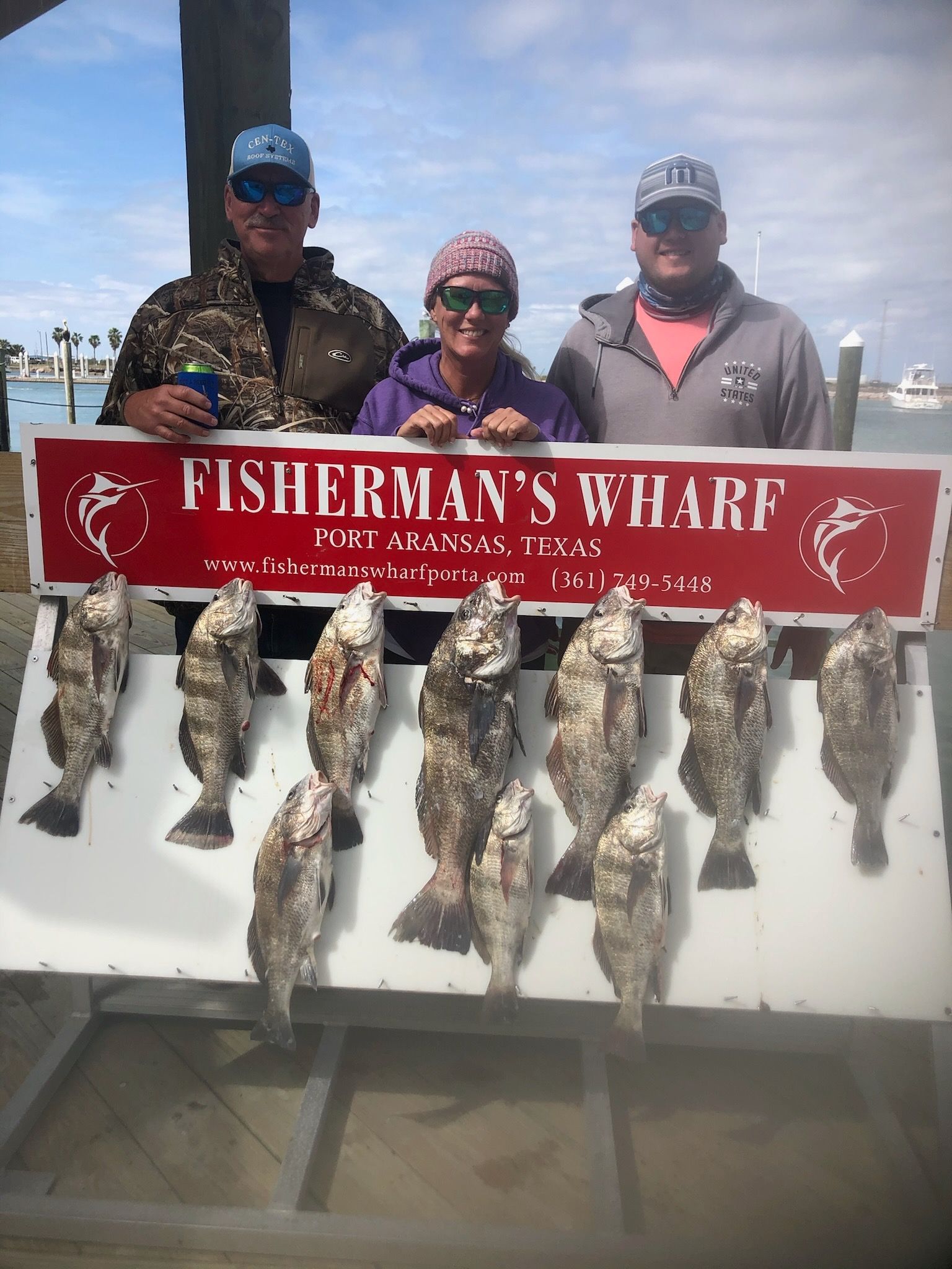 A group of people standing next to a sign that says fisherman 's wharf