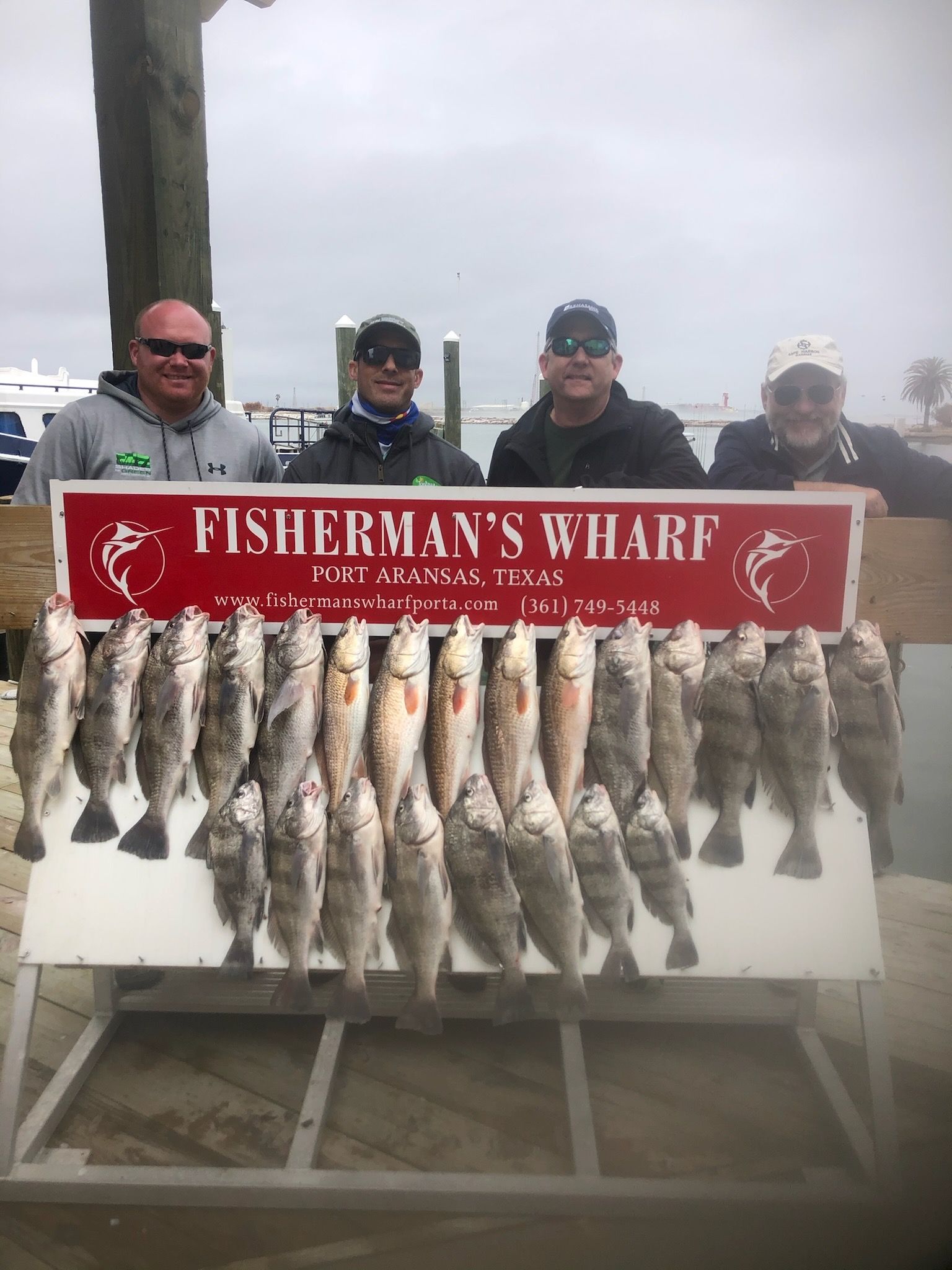 A group of men are standing next to a sign that says fisherman 's wharf.