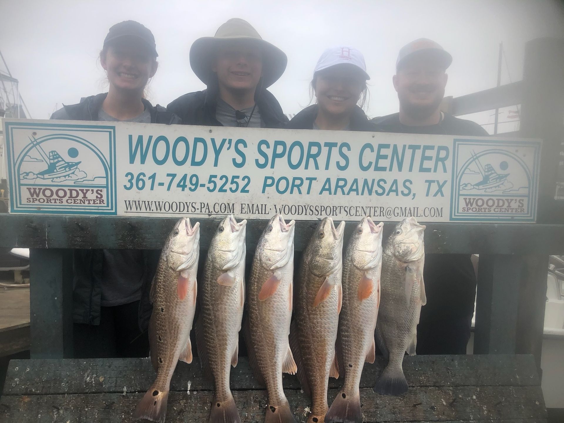 A group of people holding a sign that says woody 's sports center