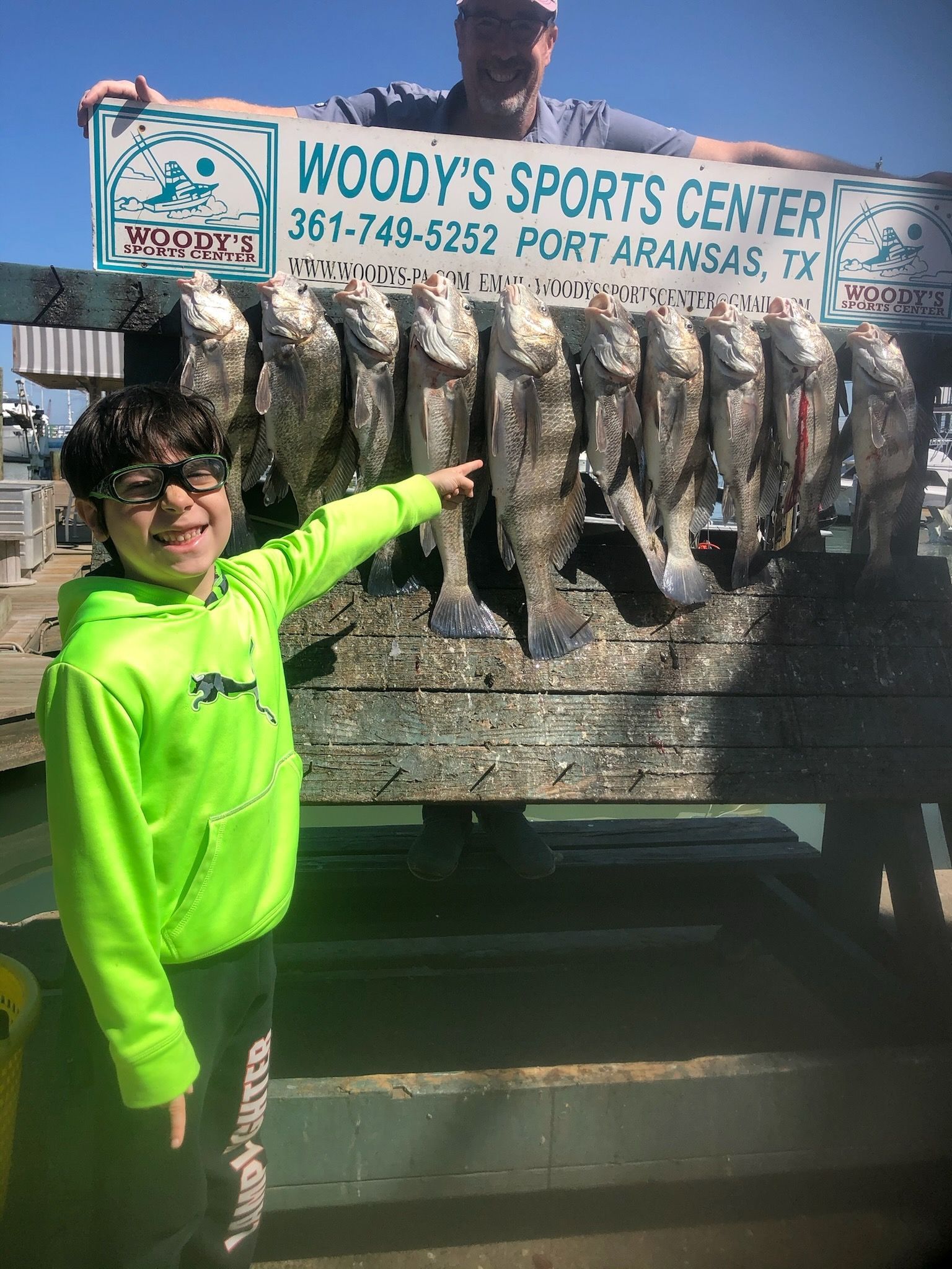 A boy is standing next to a man holding a sign that says woody 's sports center.