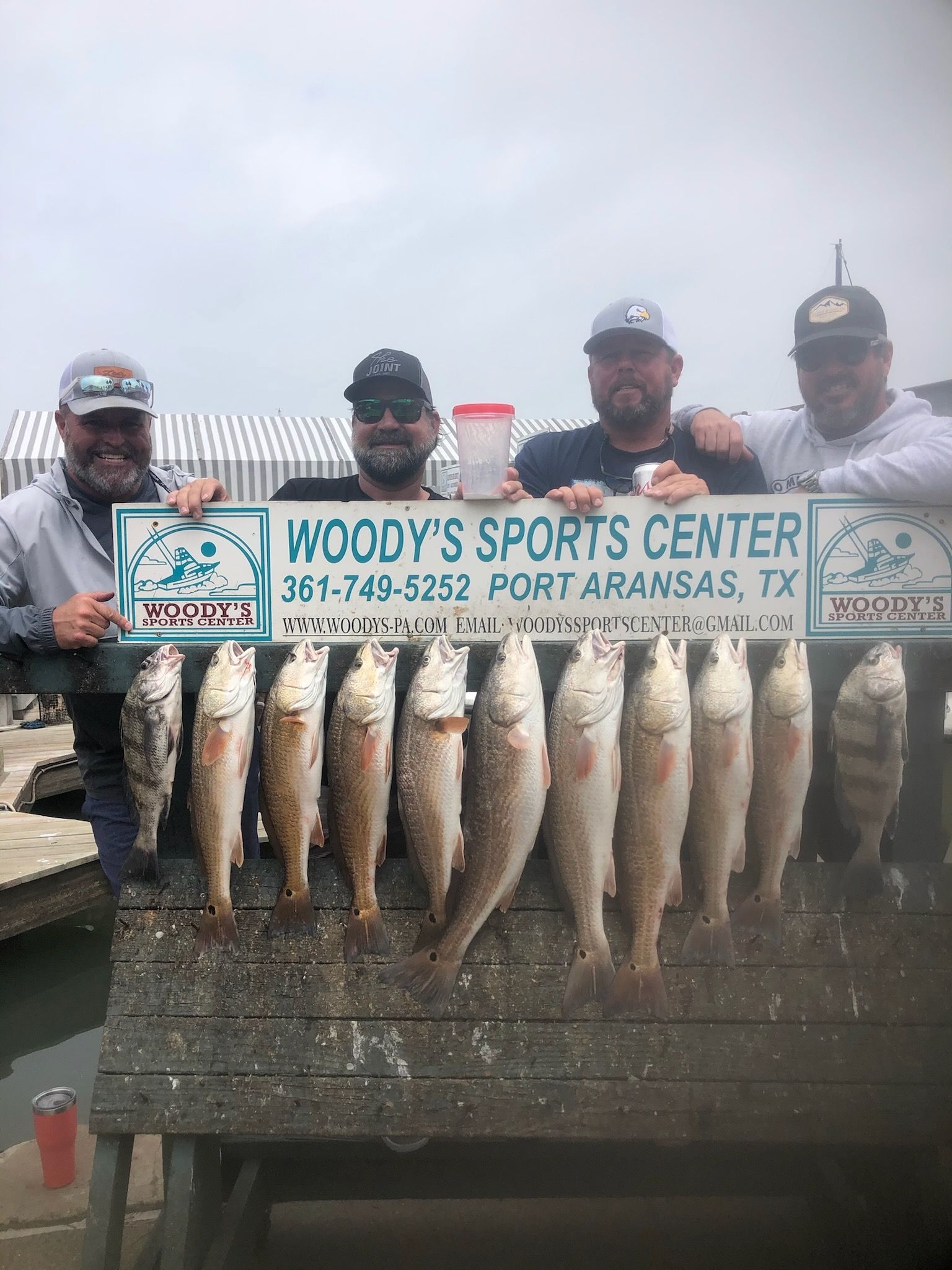 A group of men are posing for a picture with their catch of fish.