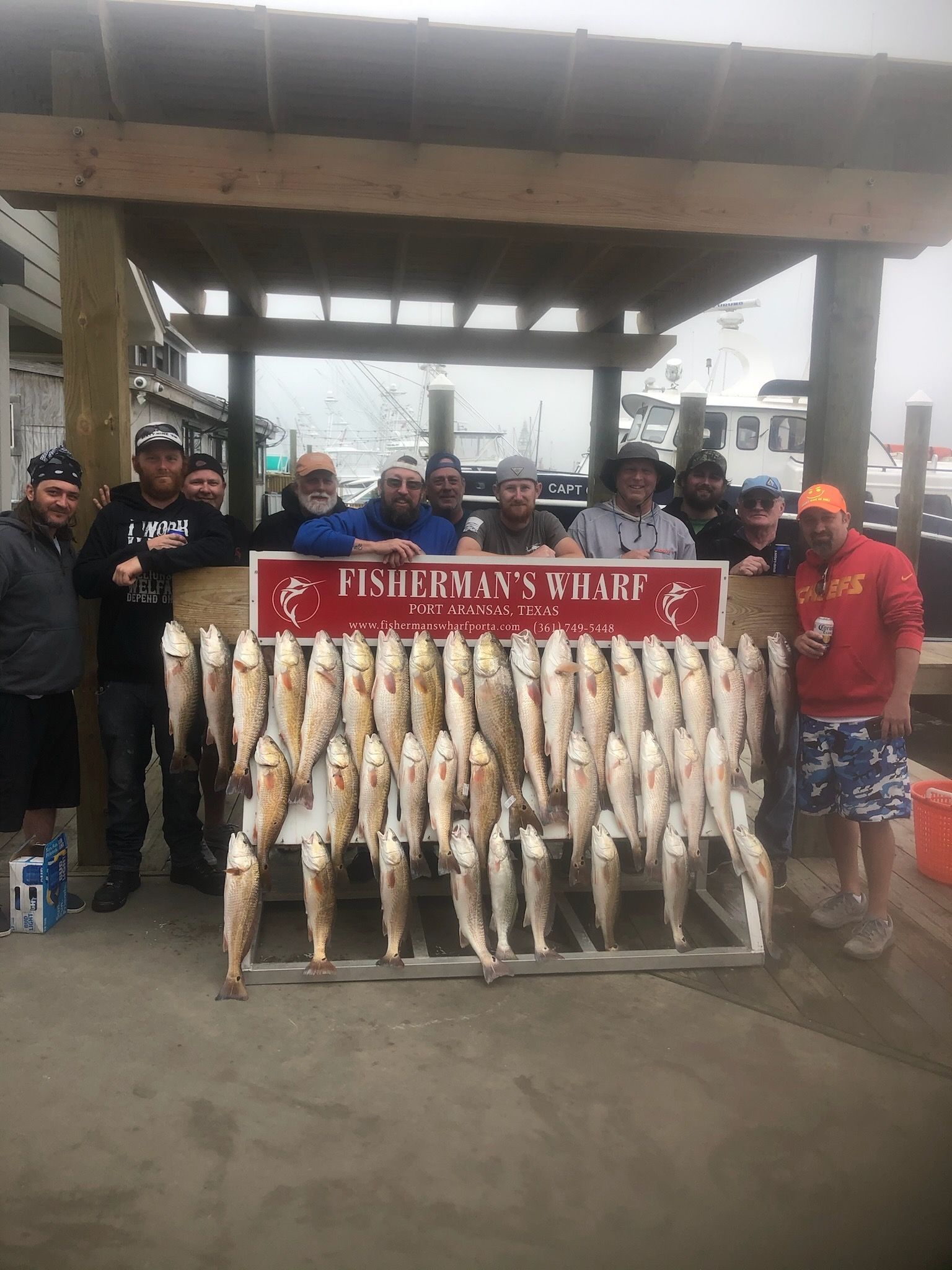 A group of men standing next to a rack of fish.