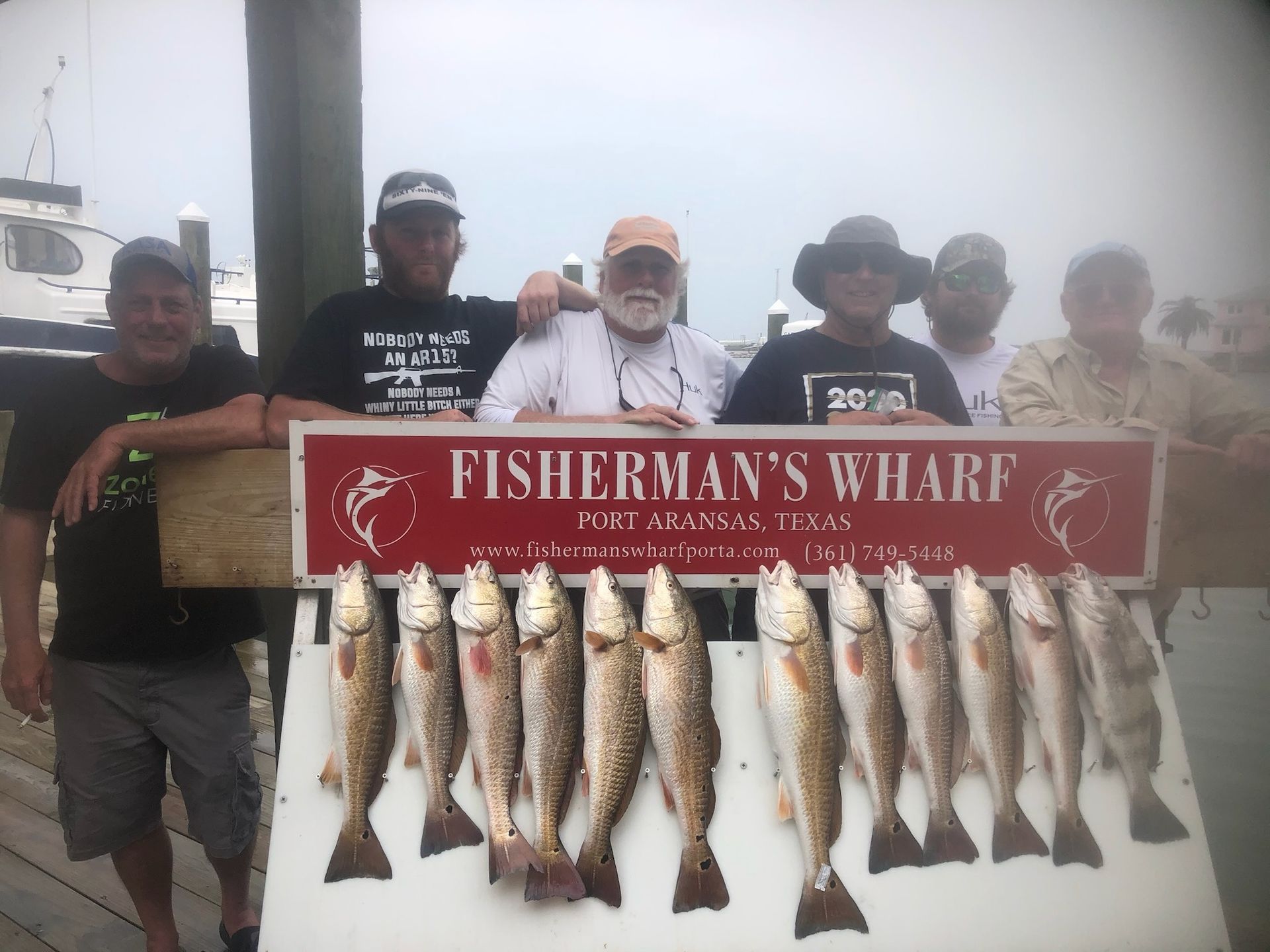 A group of men standing next to a sign that says fisherman 's wharf