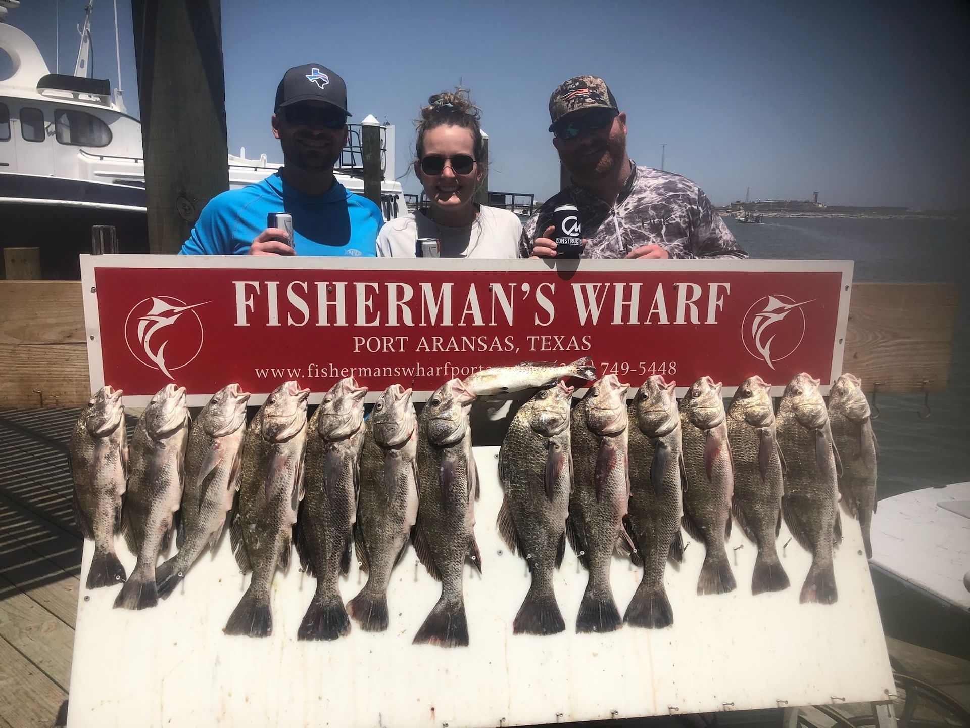 Three men are standing next to a sign that says fisherman 's wharf