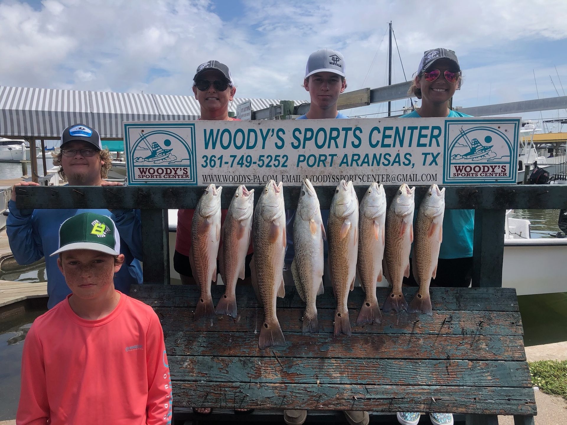A group of people standing next to each other holding a bunch of fish.