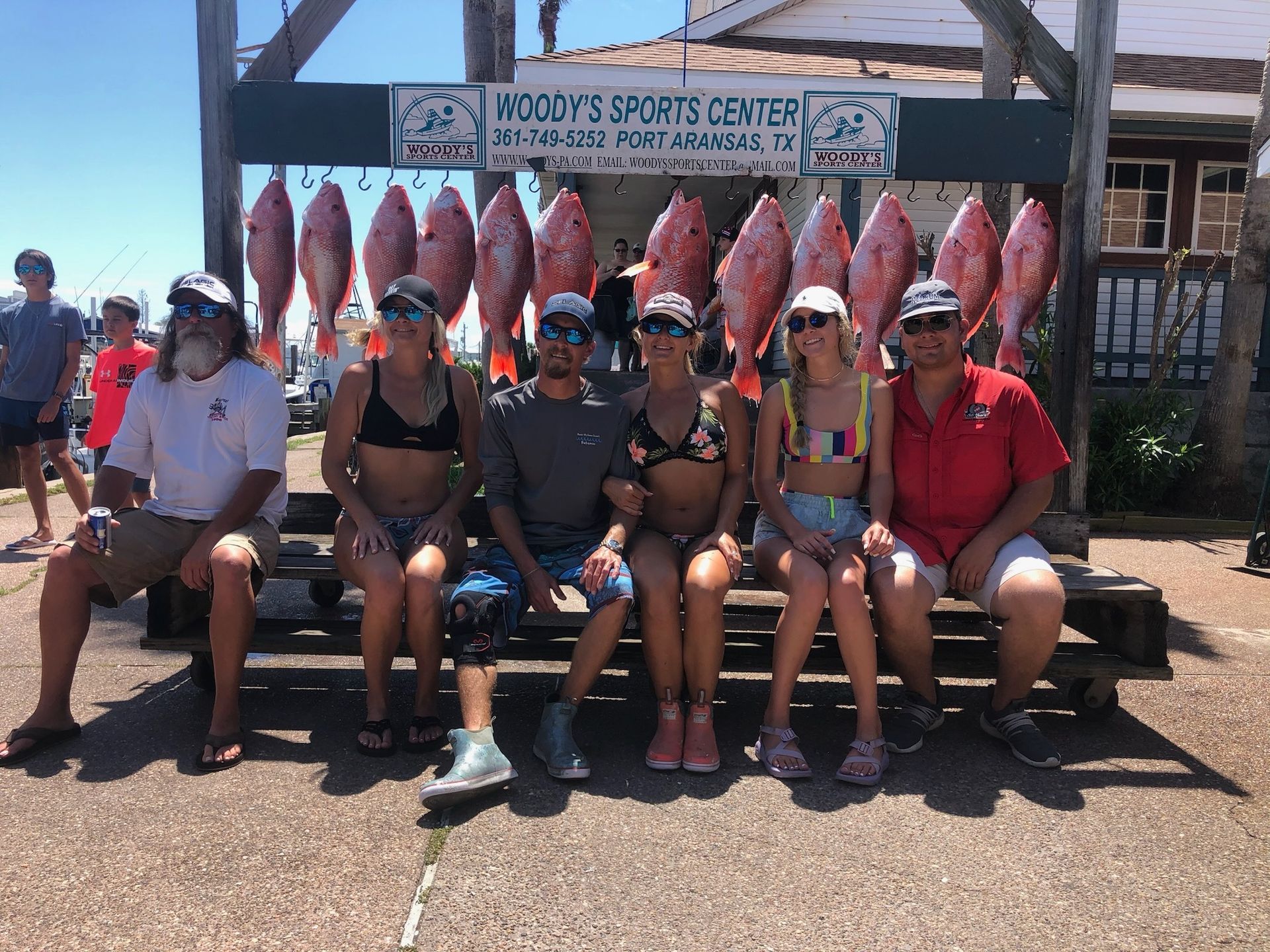 A group of people are sitting on a bench in front of a display of fish.