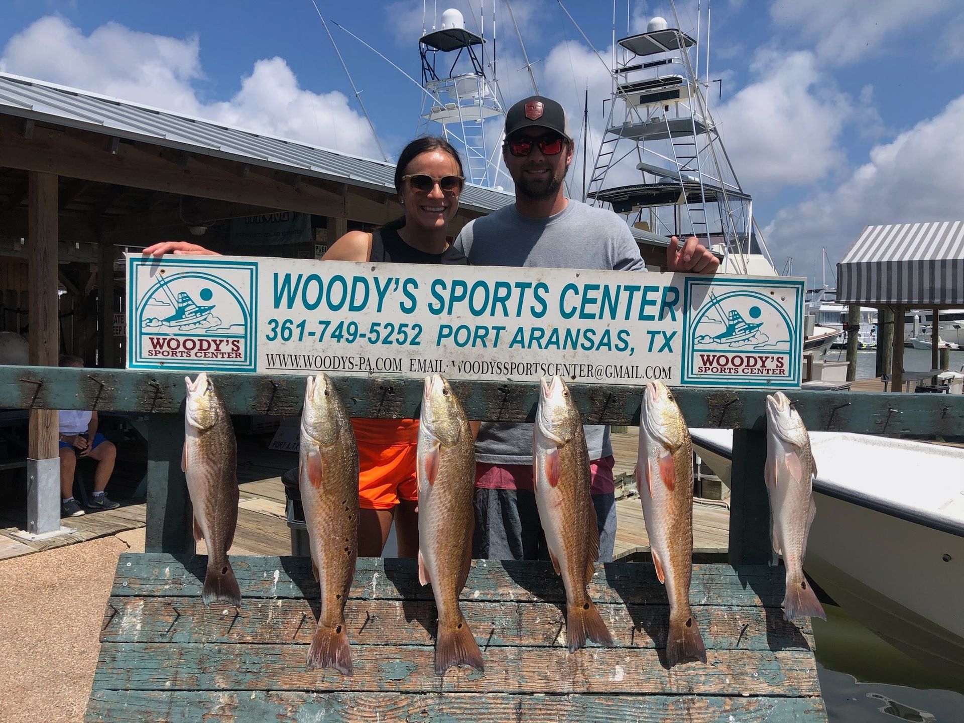 A man and a woman are holding a sign that says woody 's sports center.