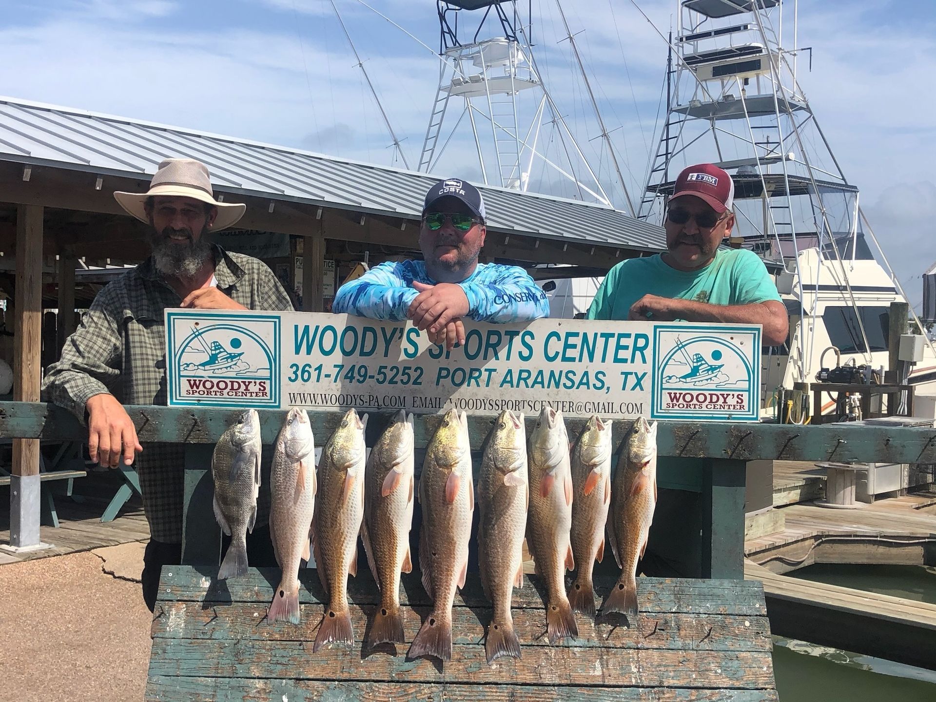 A group of men are standing next to a sign that says woody 's sports center.