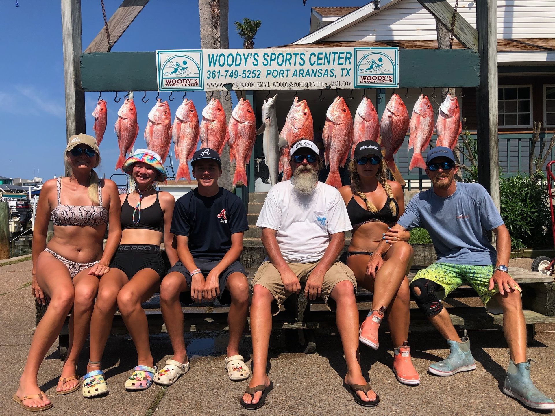 A group of people are sitting in front of a sign that says woody 's sports center