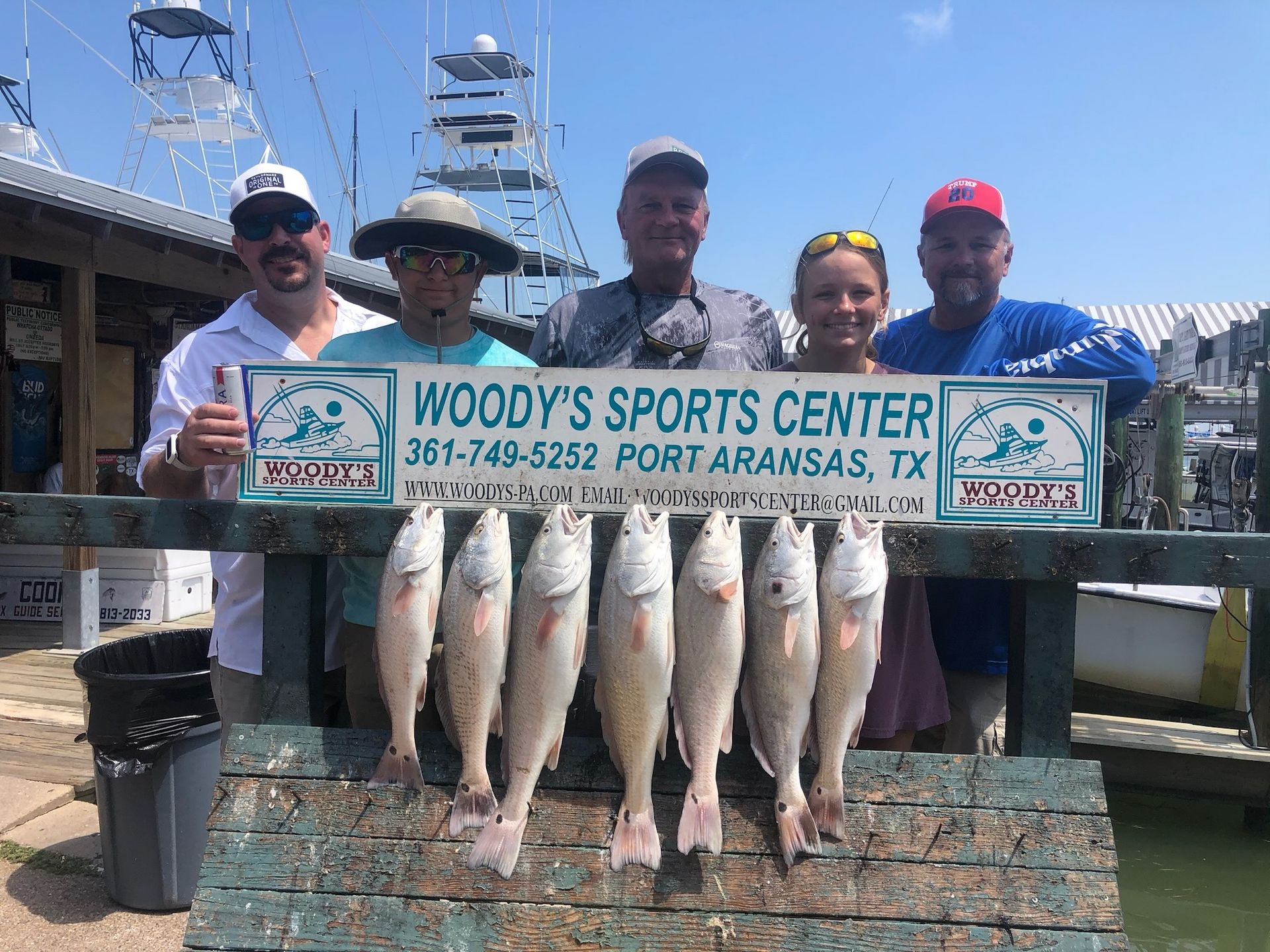A group of people standing next to each other holding a bunch of fish.