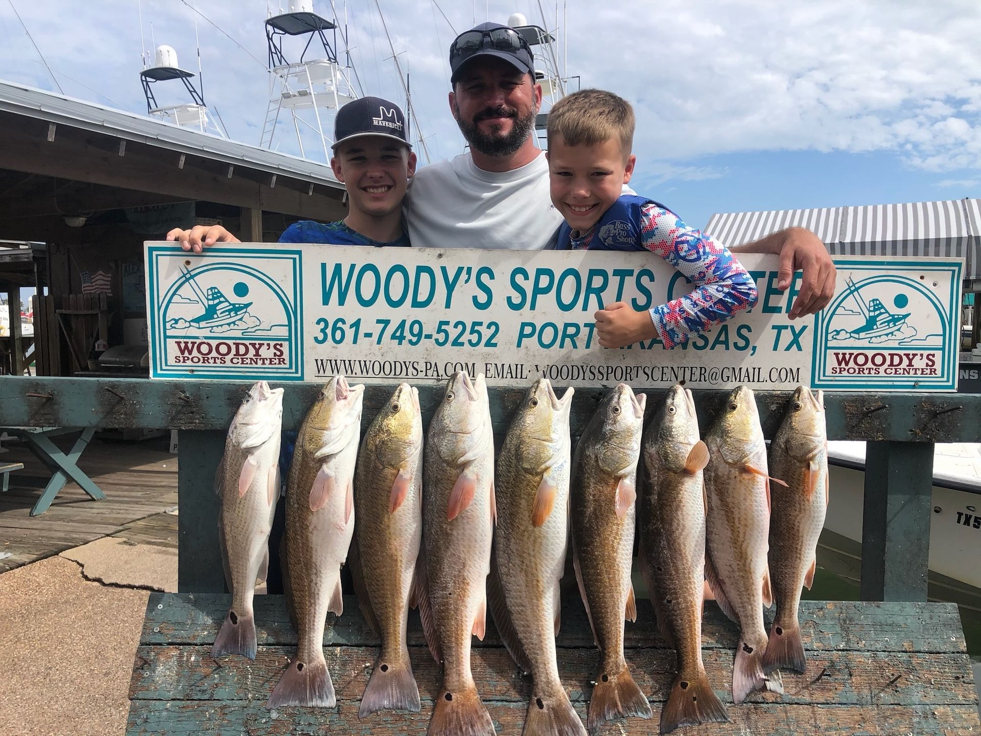 A man and two children are holding a sign that says woody 's sports.