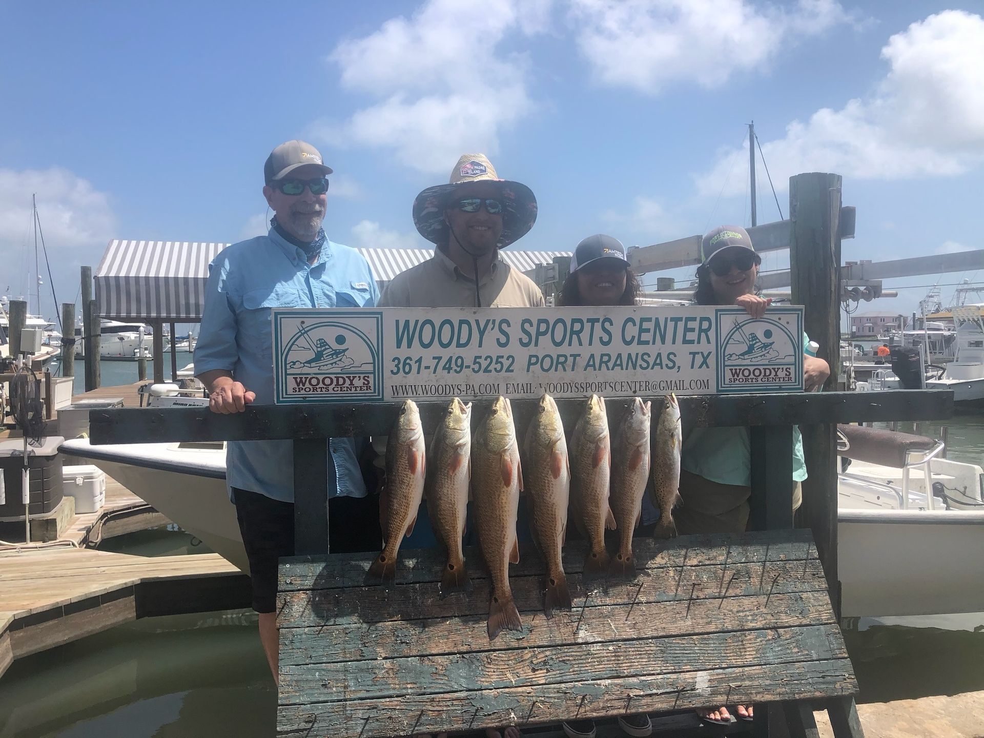 A group of people standing next to a sign that says woody 's sports center