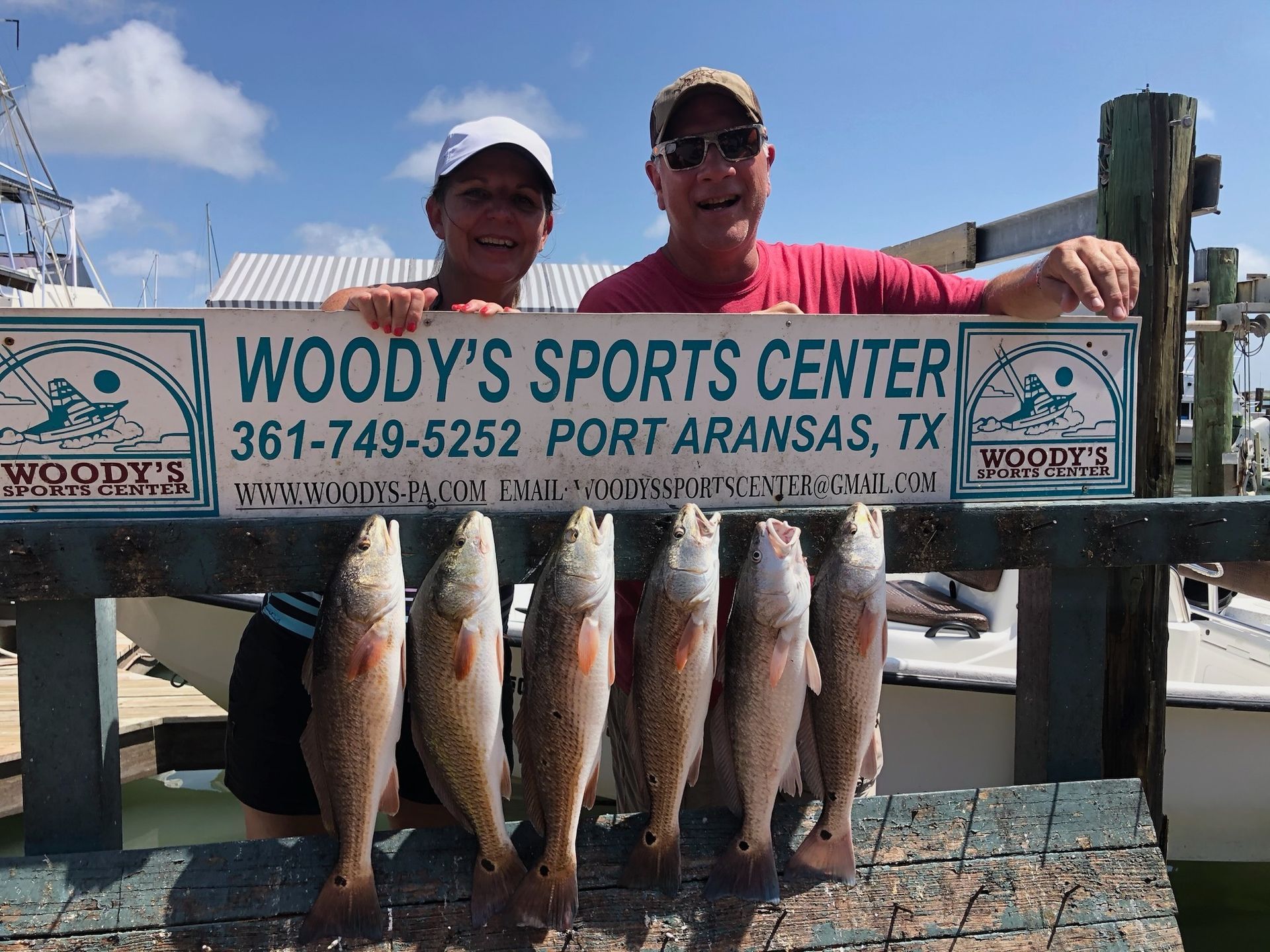 A man and a woman are holding a sign that says woody 's sports center