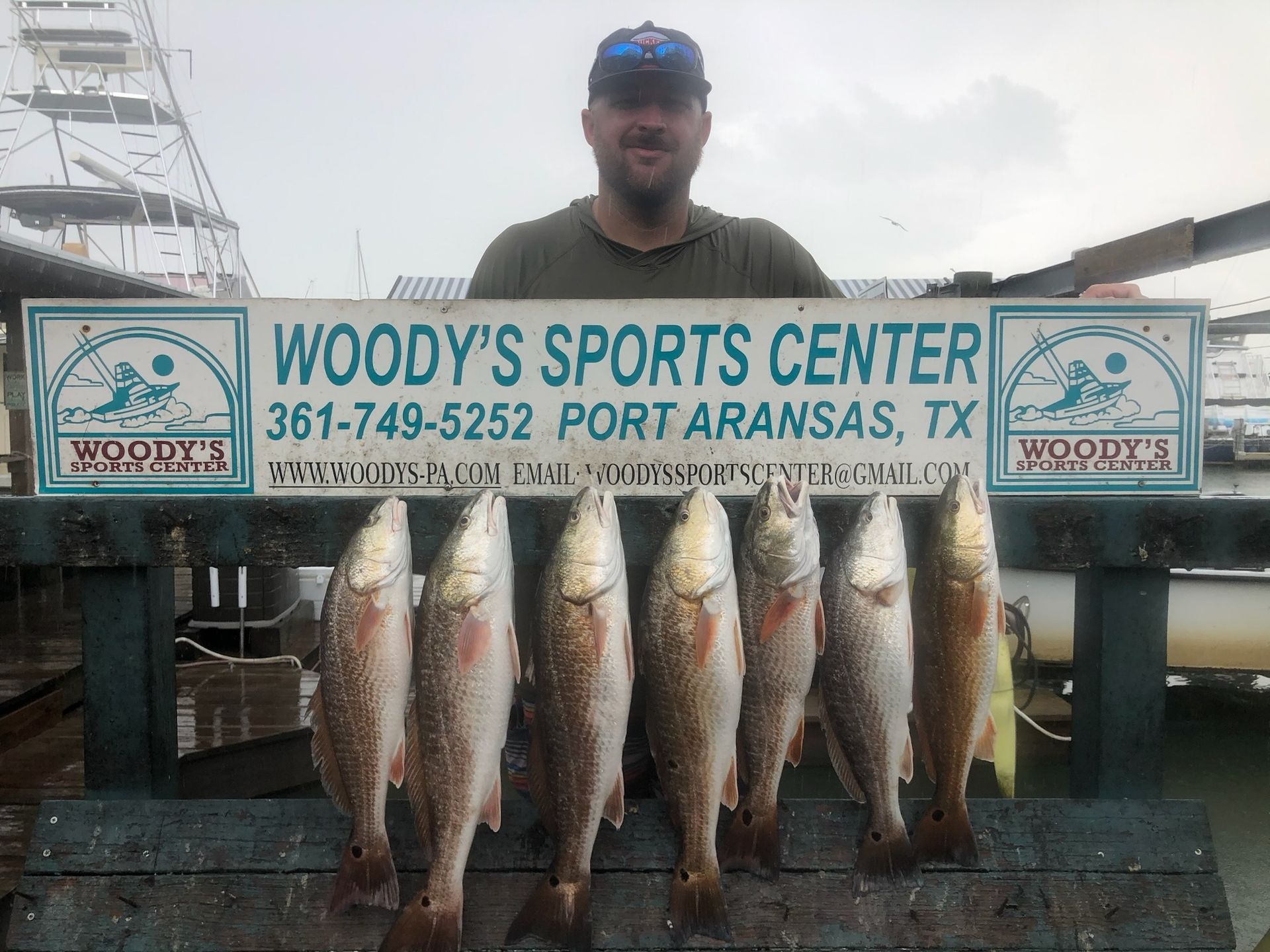 A man holding a sign that says woody 's sports center