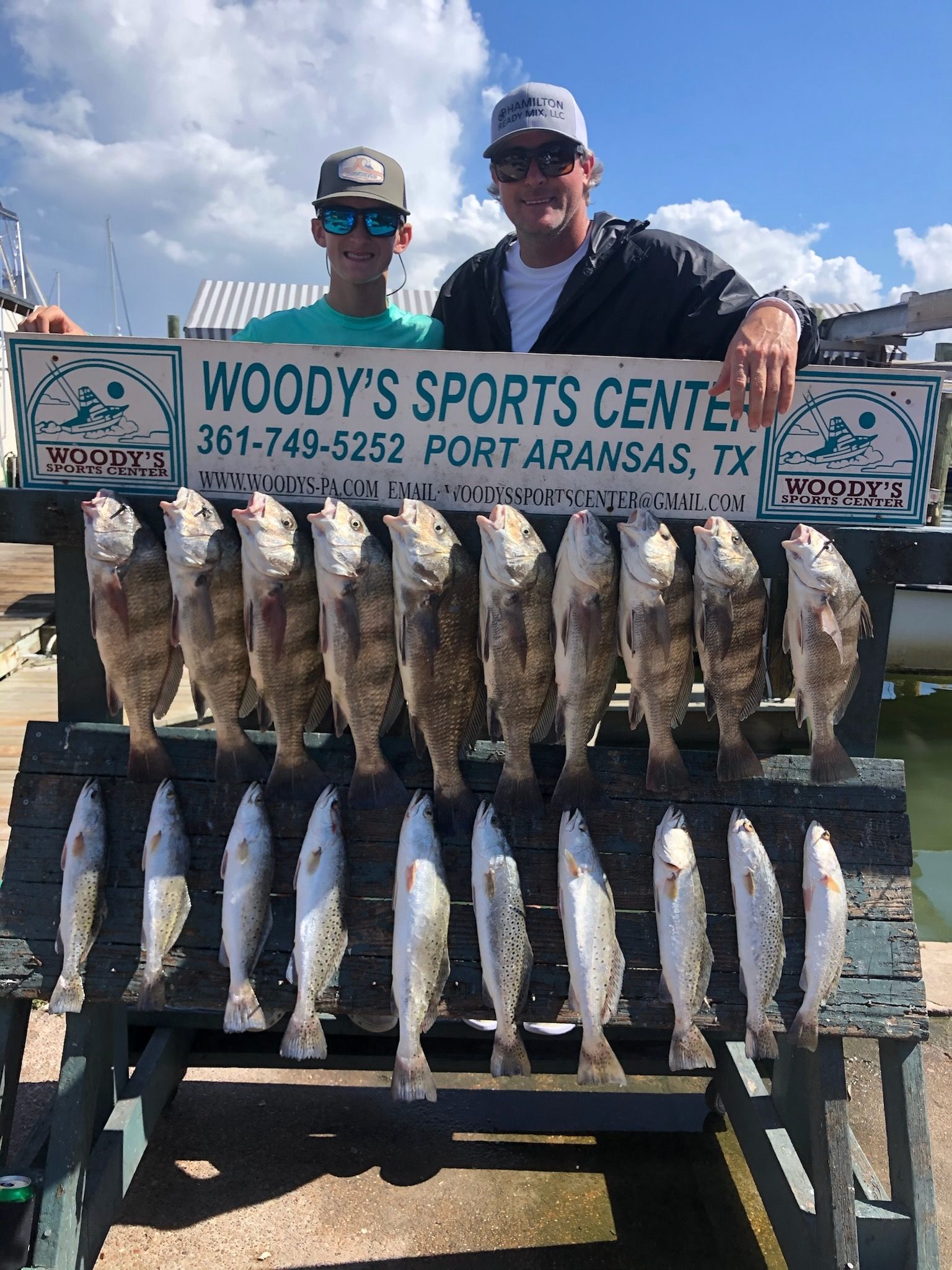 Two men are standing next to each other holding a sign that says woody 's sports center.