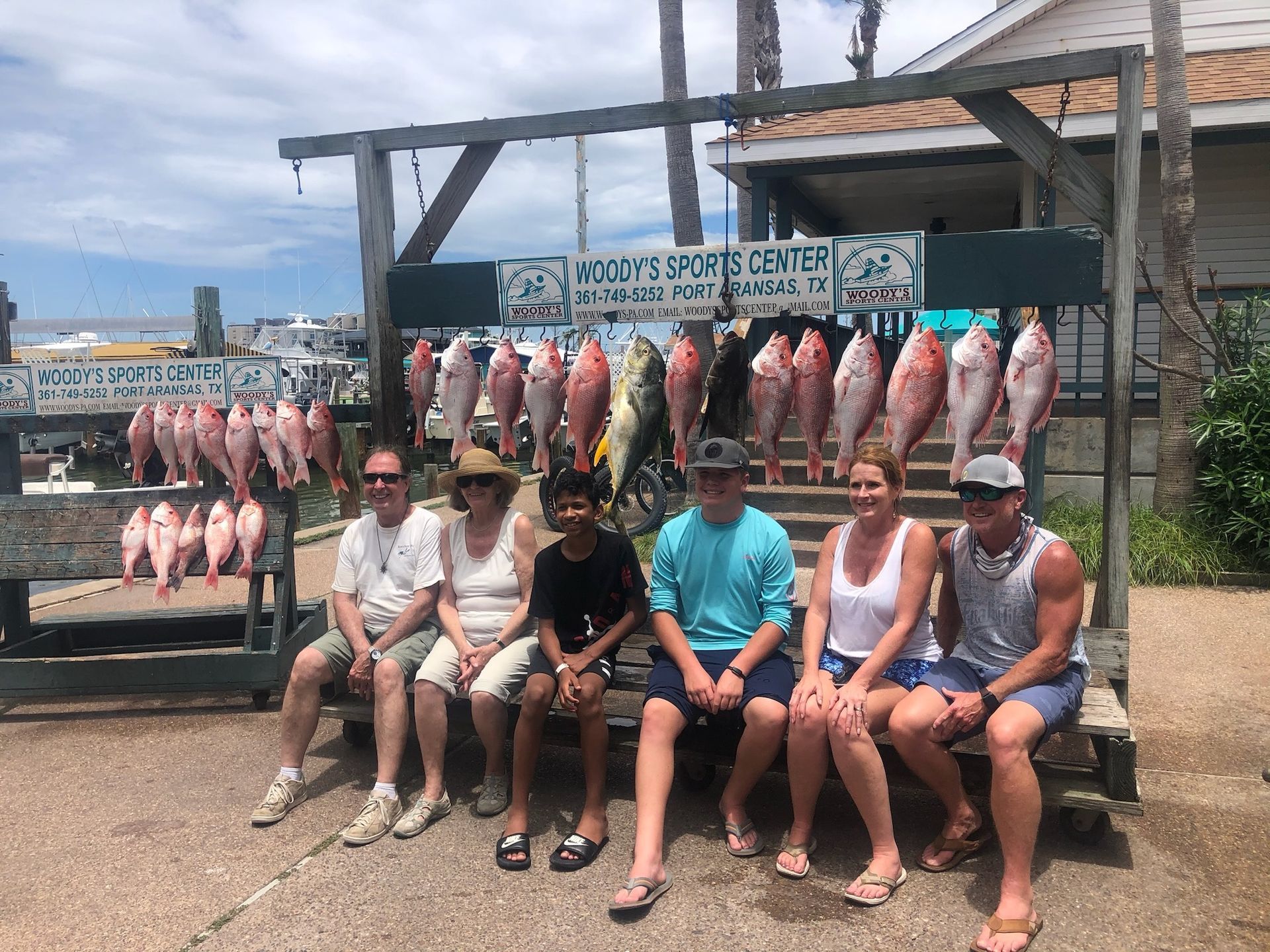 A group of people are sitting on a bench in front of a display of fish.