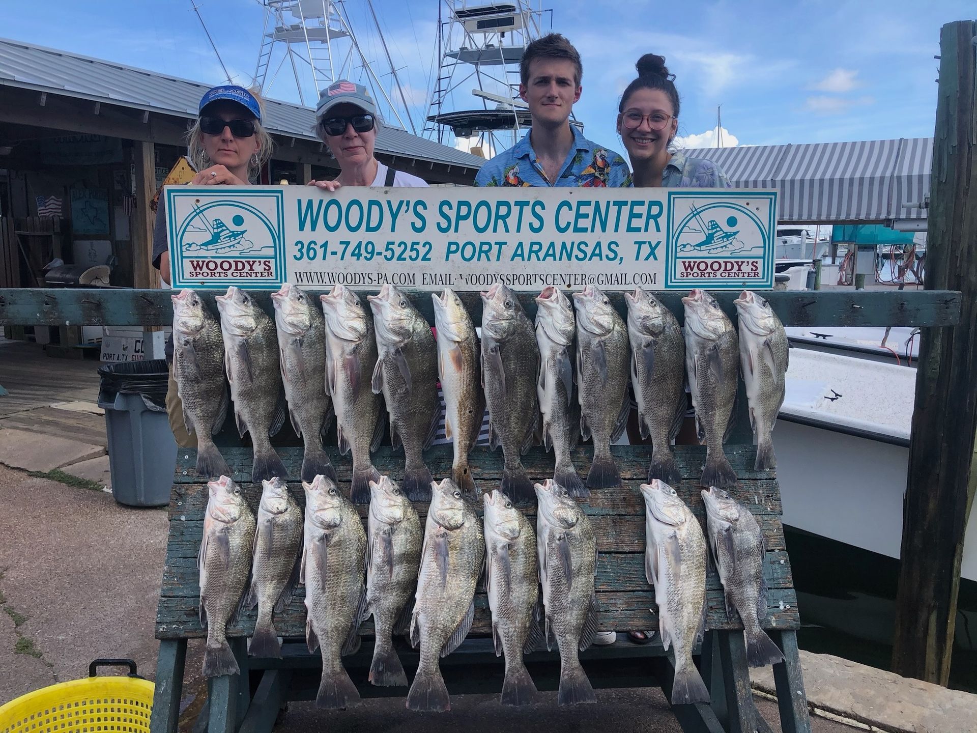 A group of people standing next to a rack of fish.