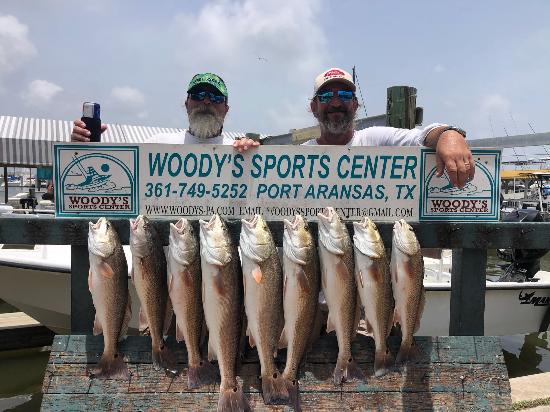 Two men are holding a sign that says woody 's sports center.