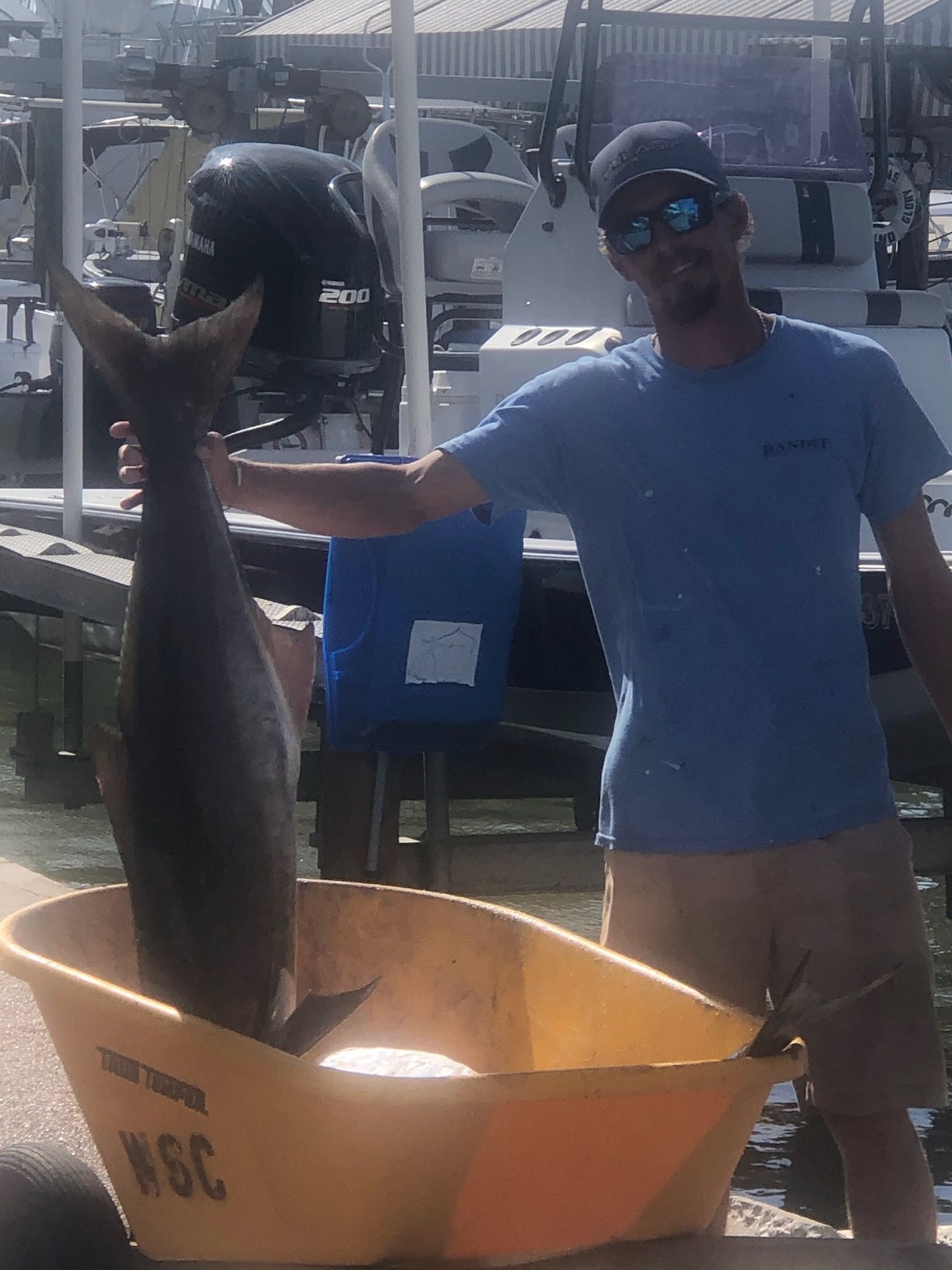 A man is holding a large fish in front of a boat.