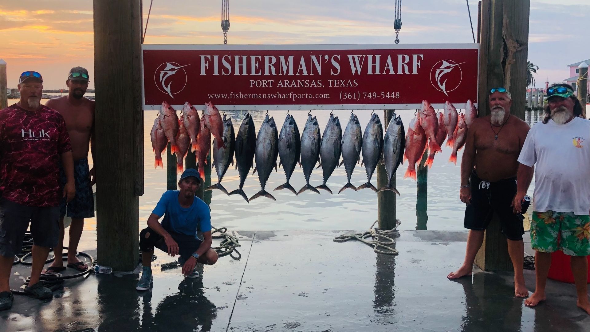 A group of men standing in front of a sign that says fisherman 's wharf