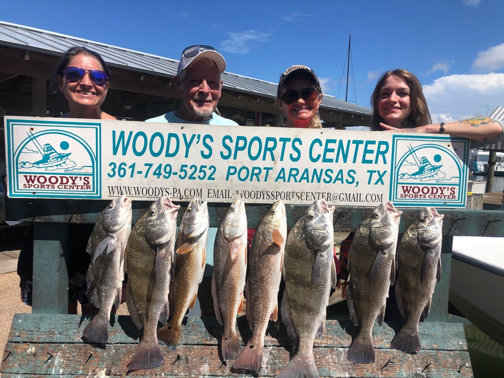 A group of people holding a sign that says woody 's sports center