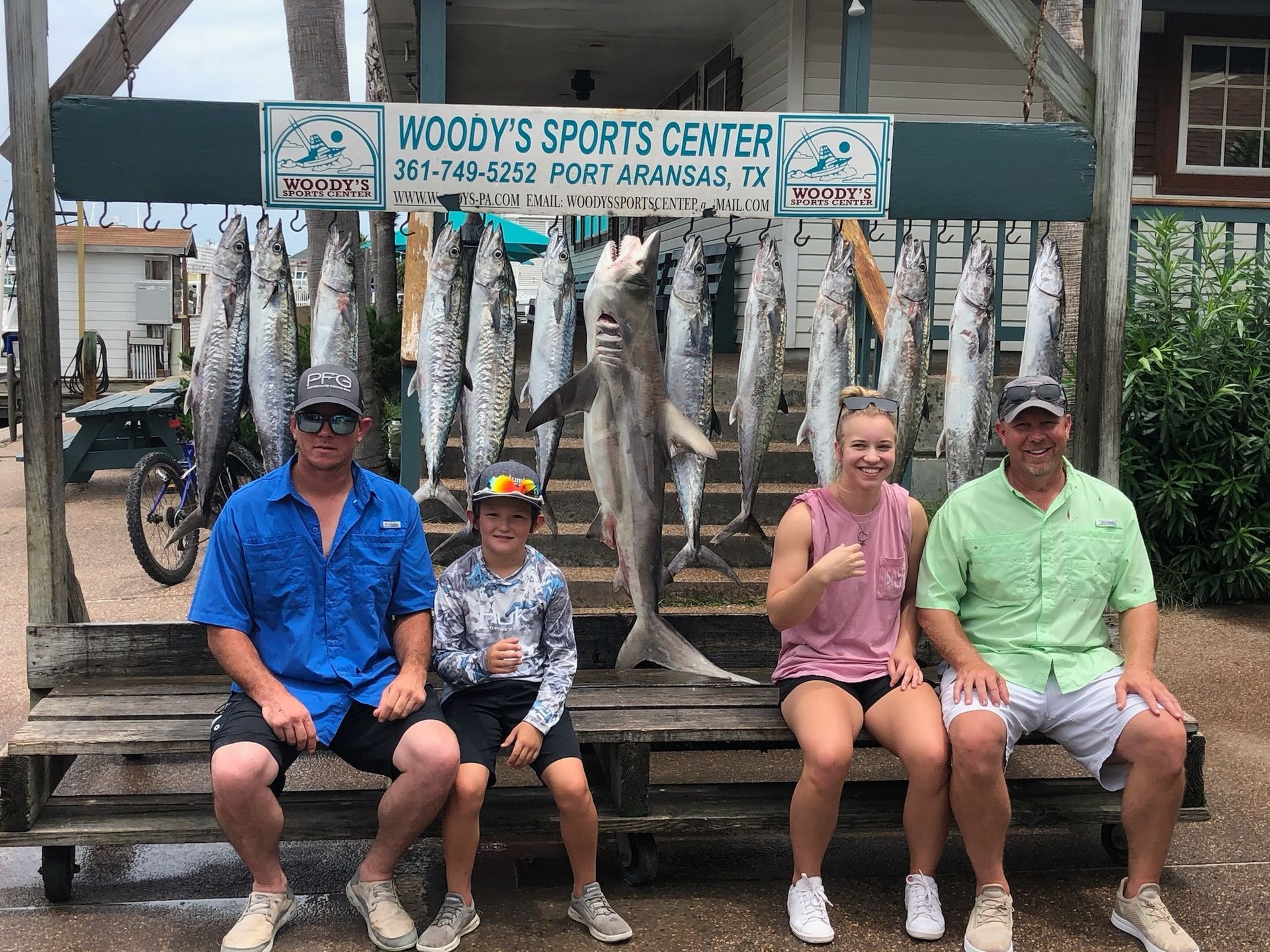 A group of people are sitting on a bench in front of a display of fish.