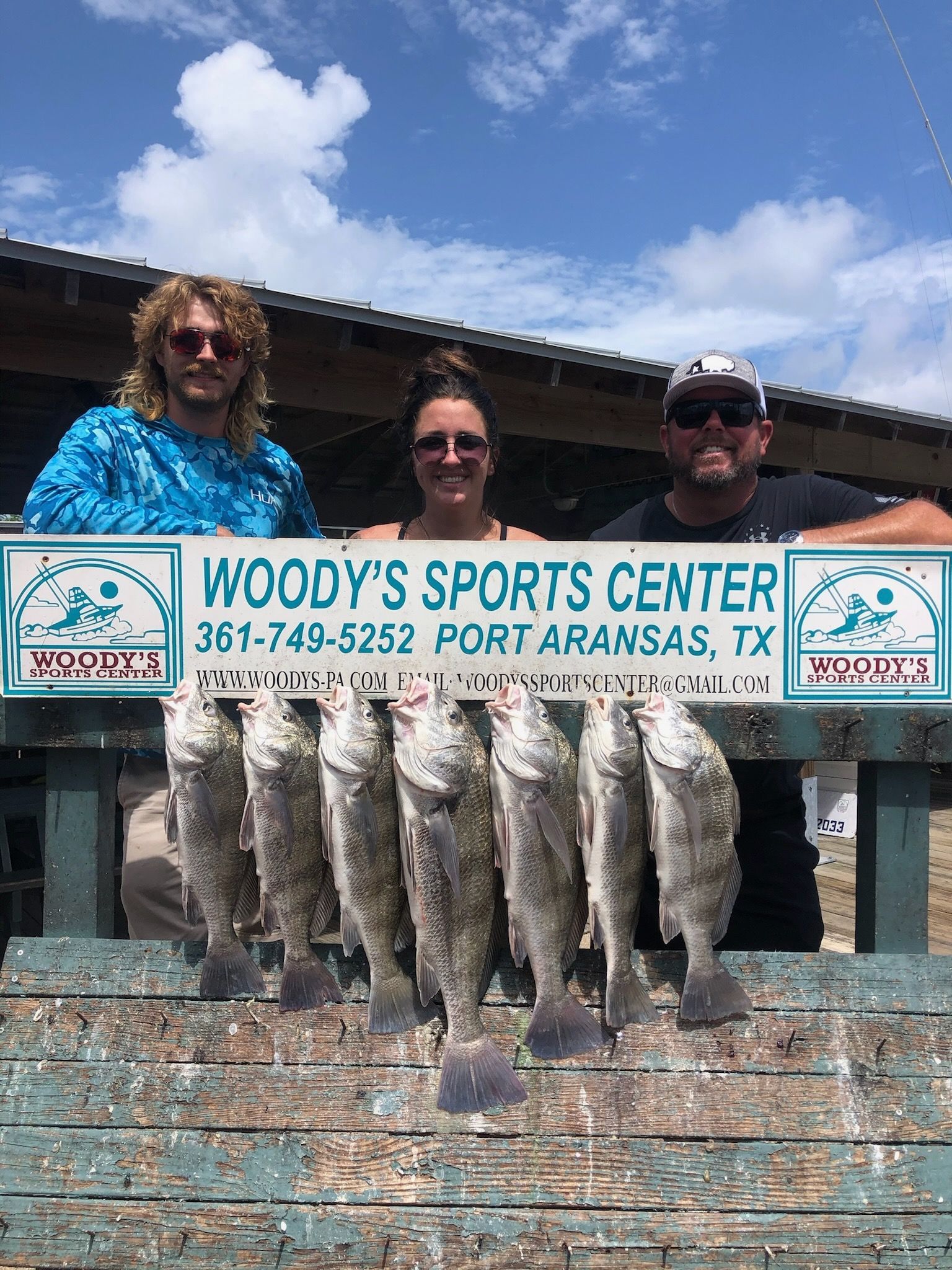 A group of people standing next to each other holding a bunch of fish.