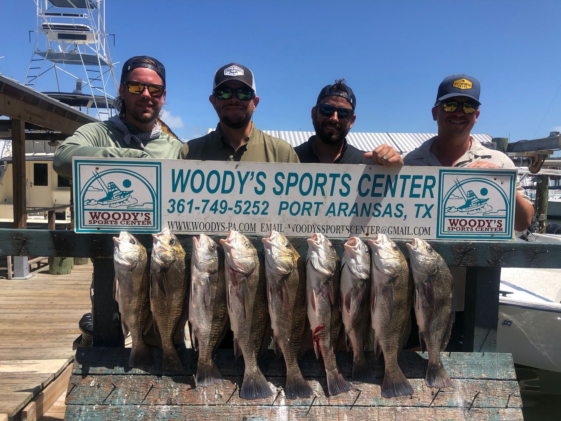 A group of men are holding a sign that says woody 's sports center.