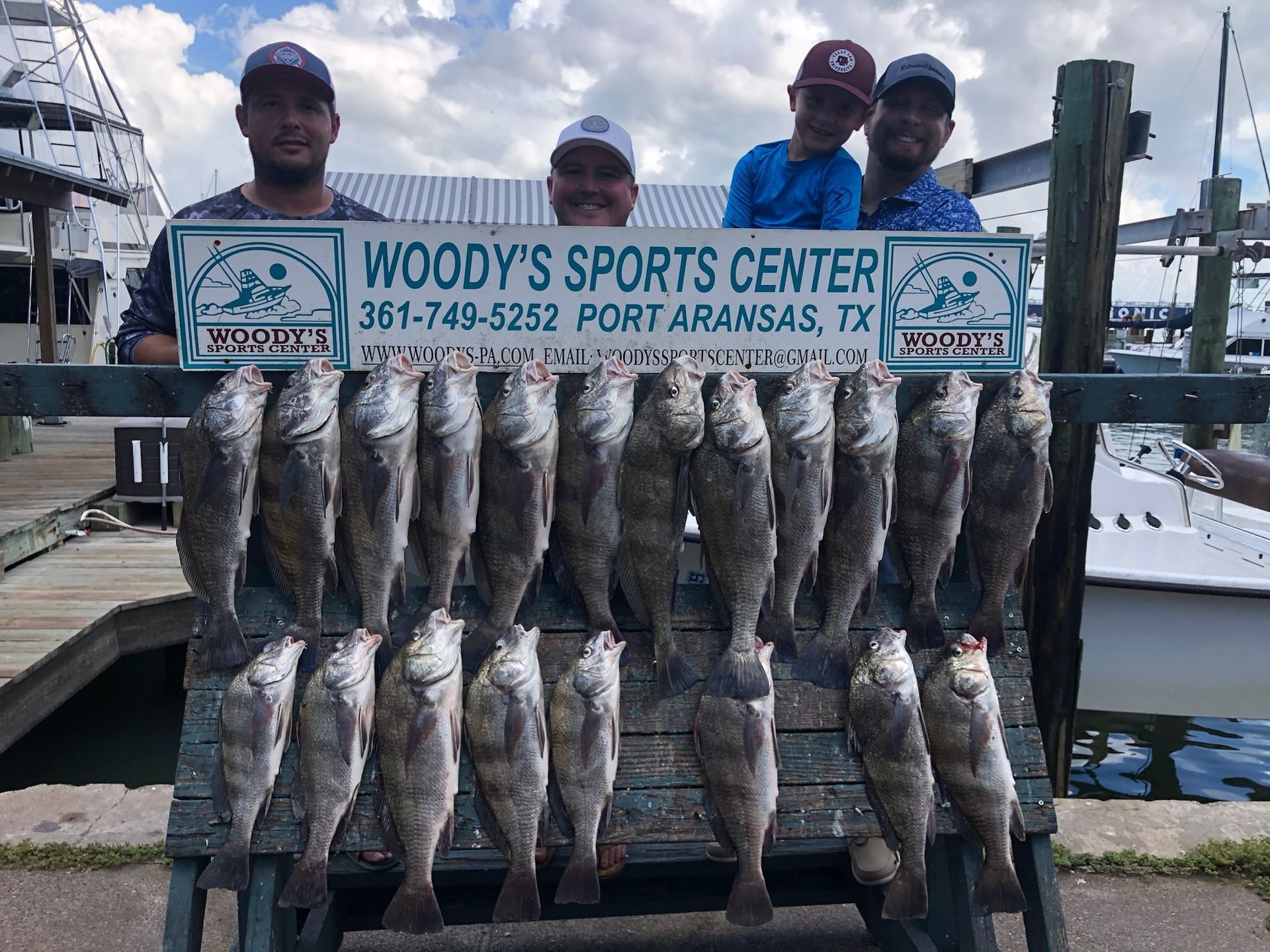 A group of men are posing for a picture with a sign that says woody 's sports center.