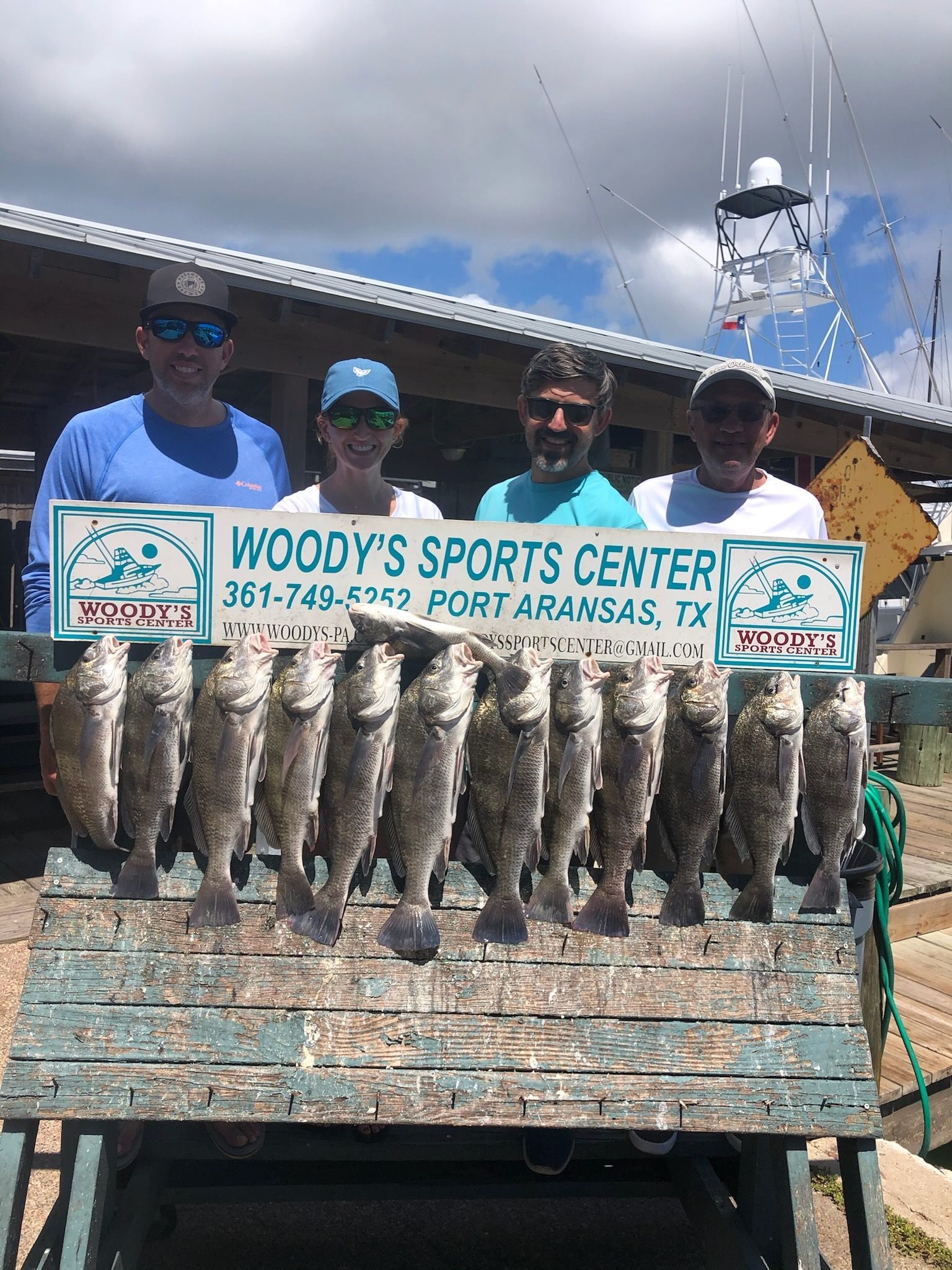 A group of people standing next to each other holding a bunch of fish.