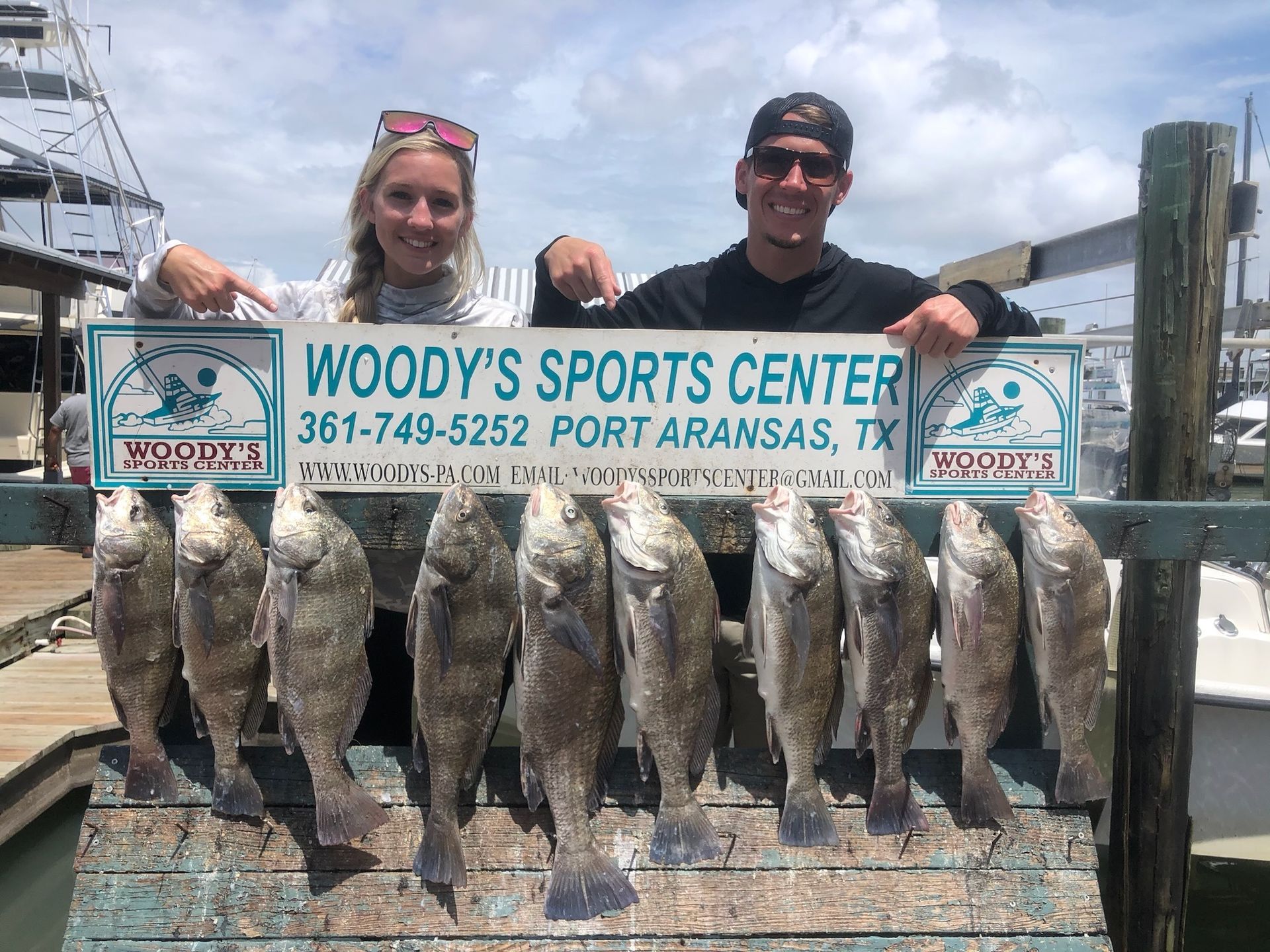 A man and a woman are holding a sign that says woody 's sports center