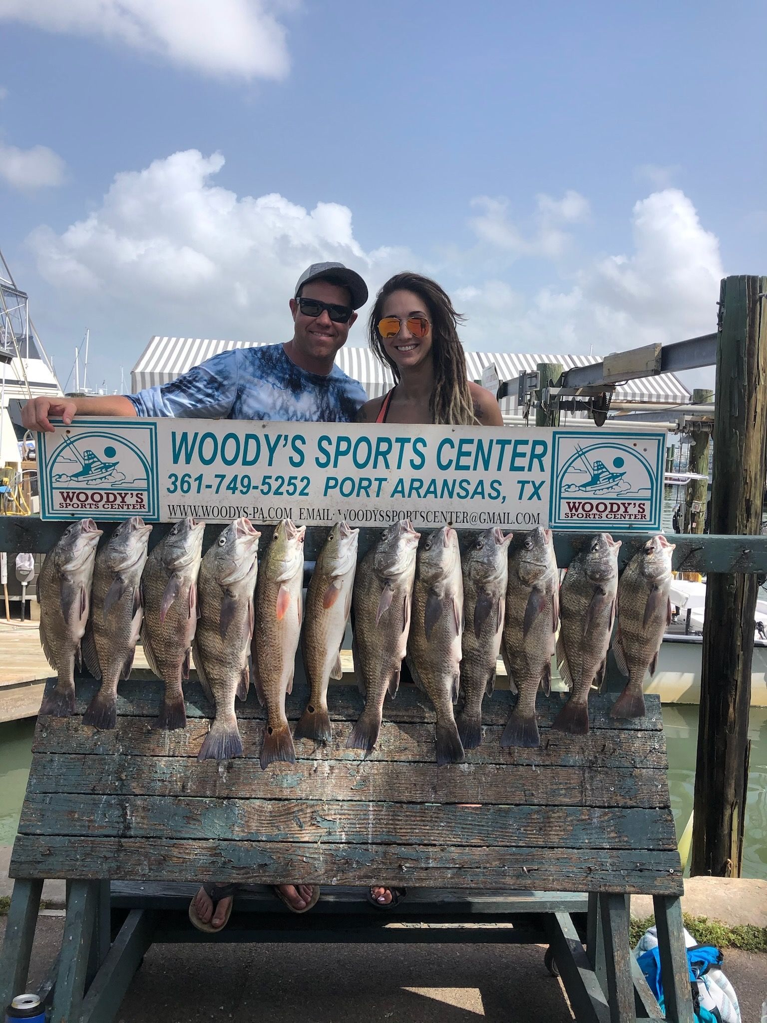 A man and a woman are posing for a picture with a bunch of fish.