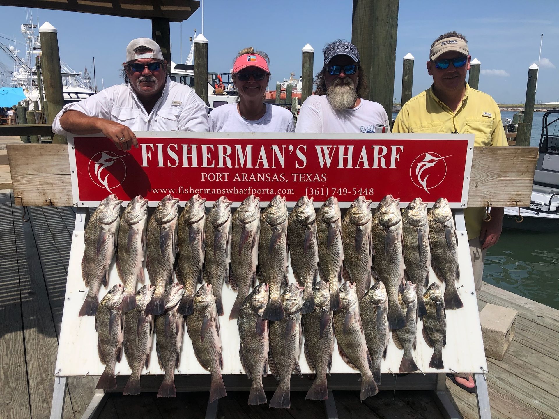 A group of men standing next to a sign that says fisherman 's wharf