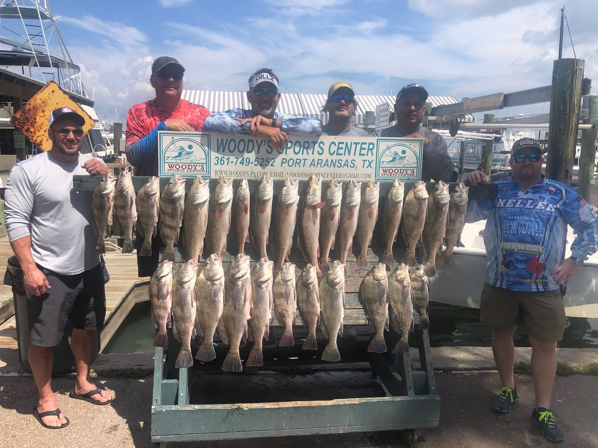 A group of men are standing next to a cart full of fish.